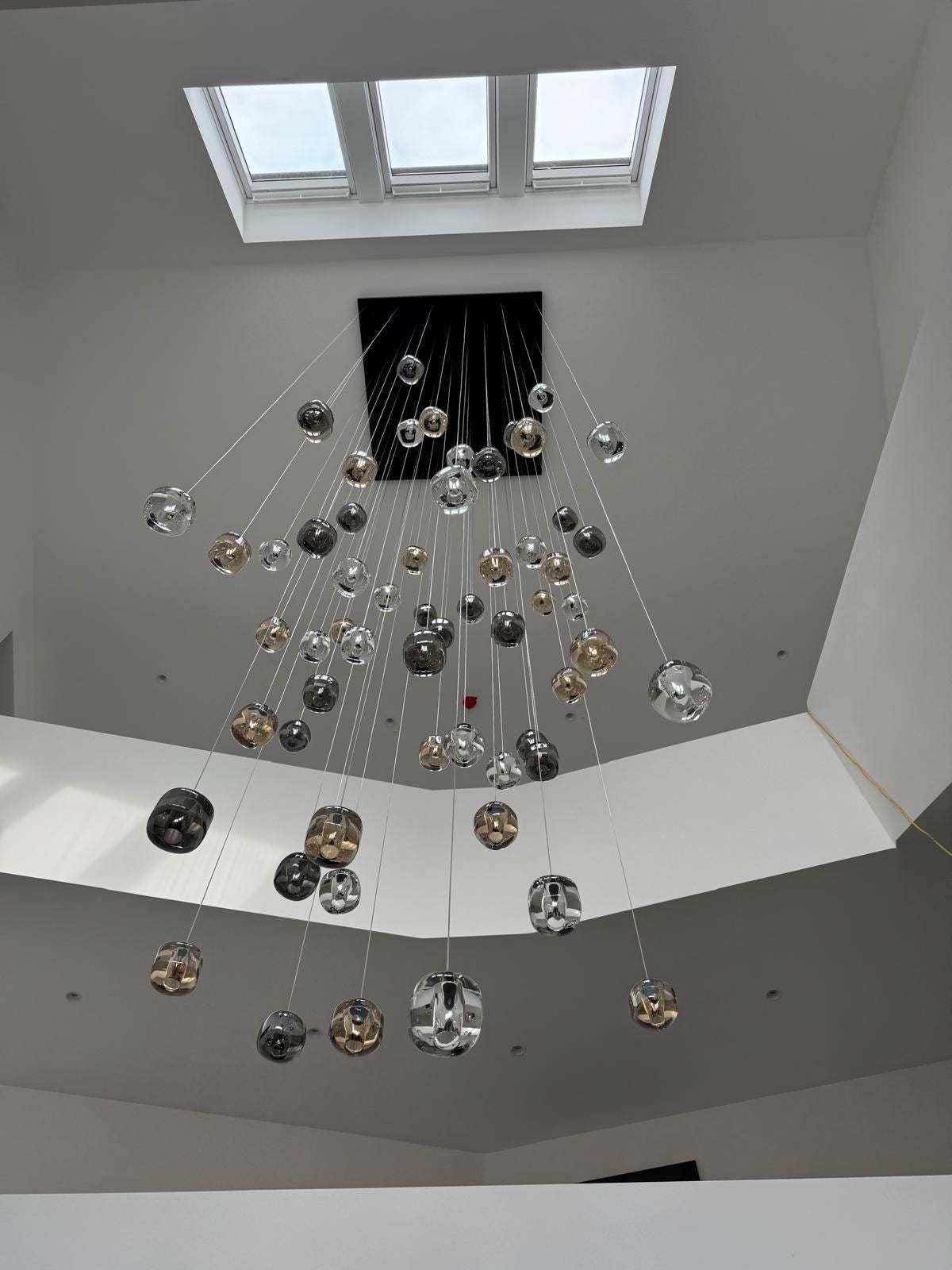 Luxury crystal pendant staircase chandelier with long drop design by VORELLI®, suspended in a modern architectural stairwell