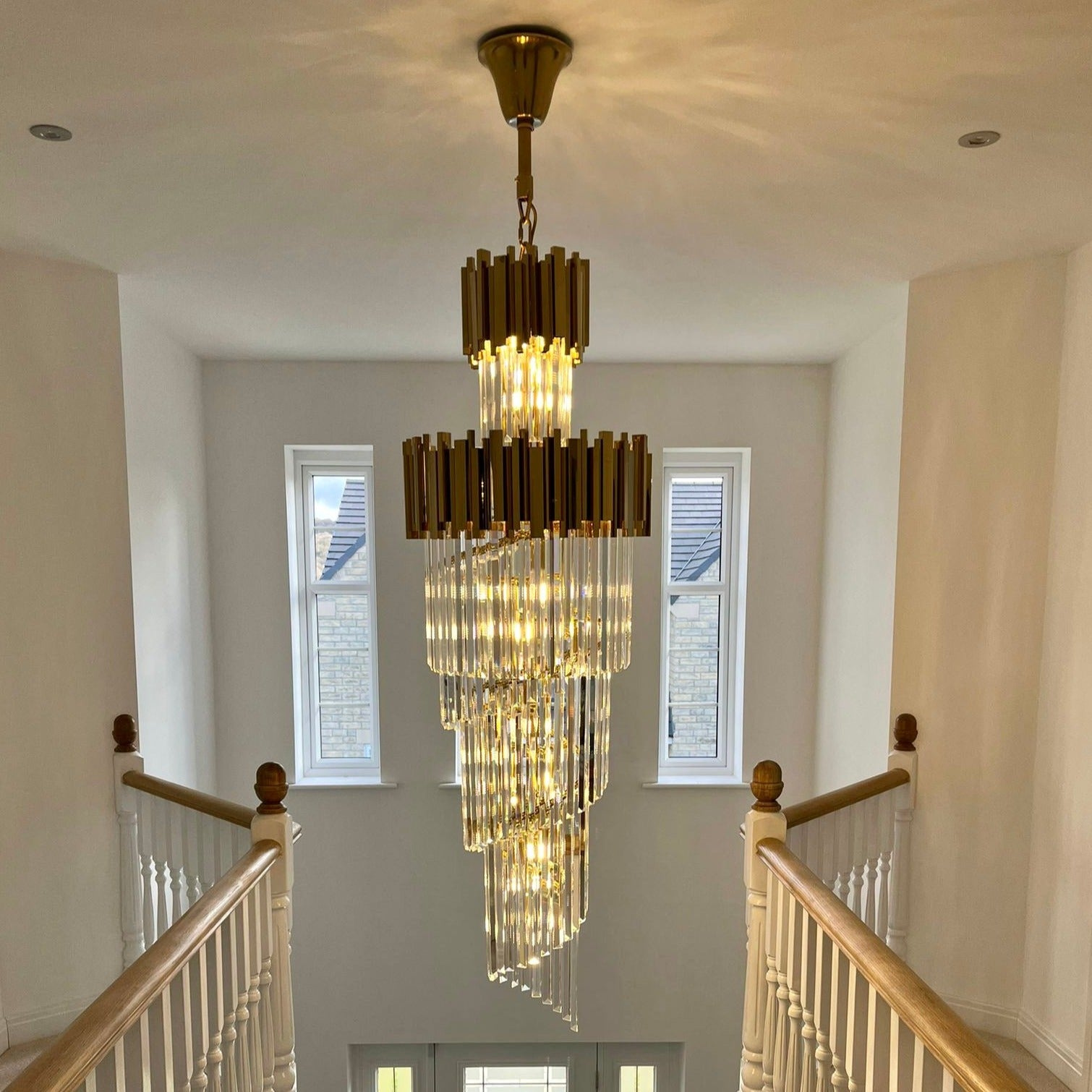 Boeotia Spiral Staircase Chandelier II installed in a warm-toned hallway, highlighting its illuminated spiral crystal structure.