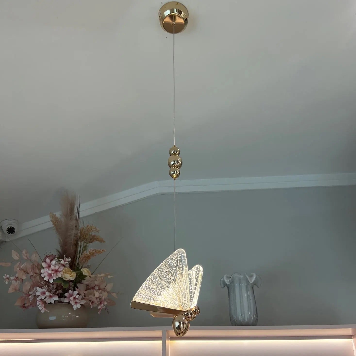 Butterfly Pendant Light against a deep blue backdrop, featuring luminous butterfly-shaped glass elements for a magical ambience.