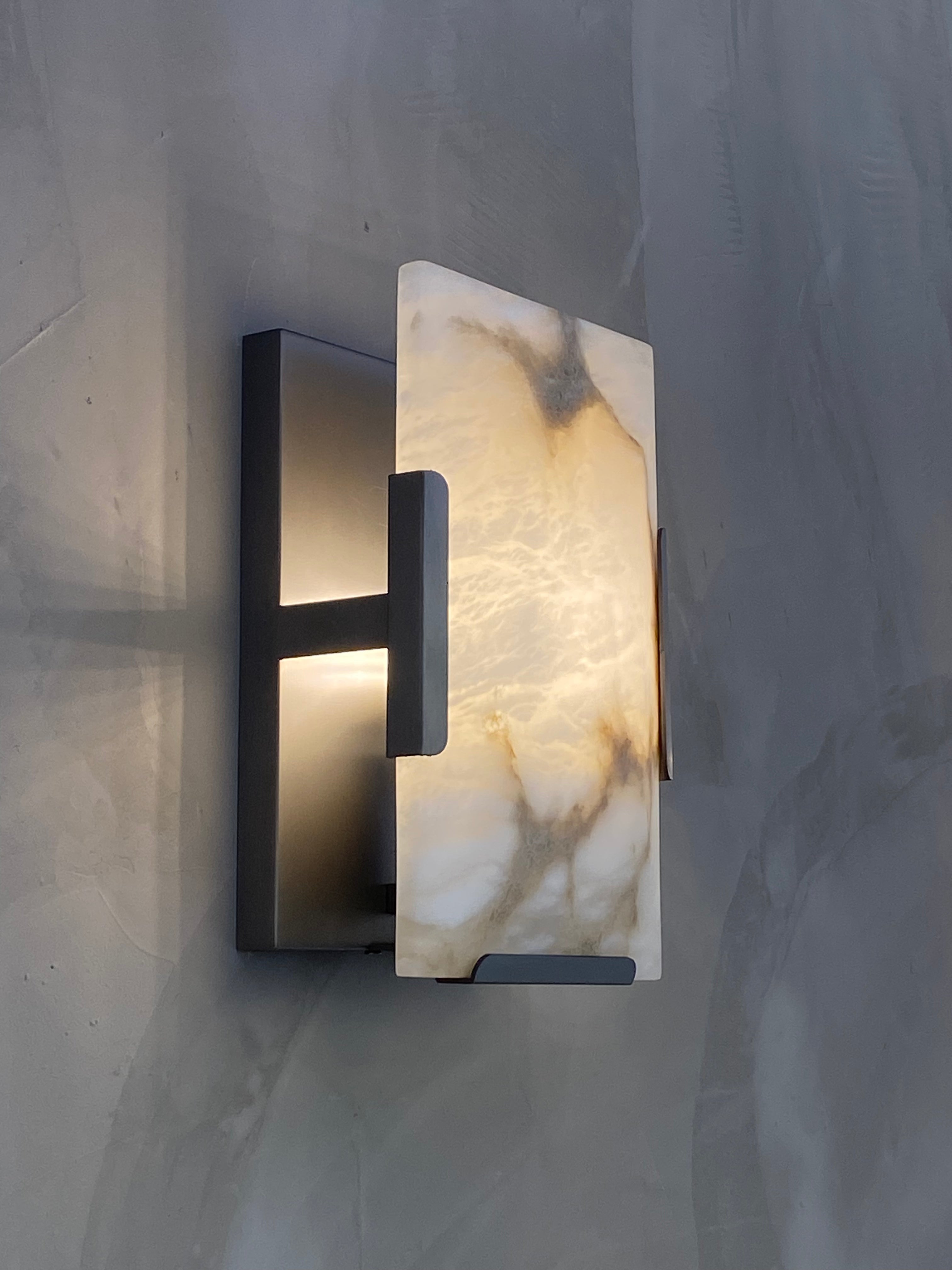 Side view of the Angel Wall Light showing its minimalist industrial frame and sculptural marble panel.