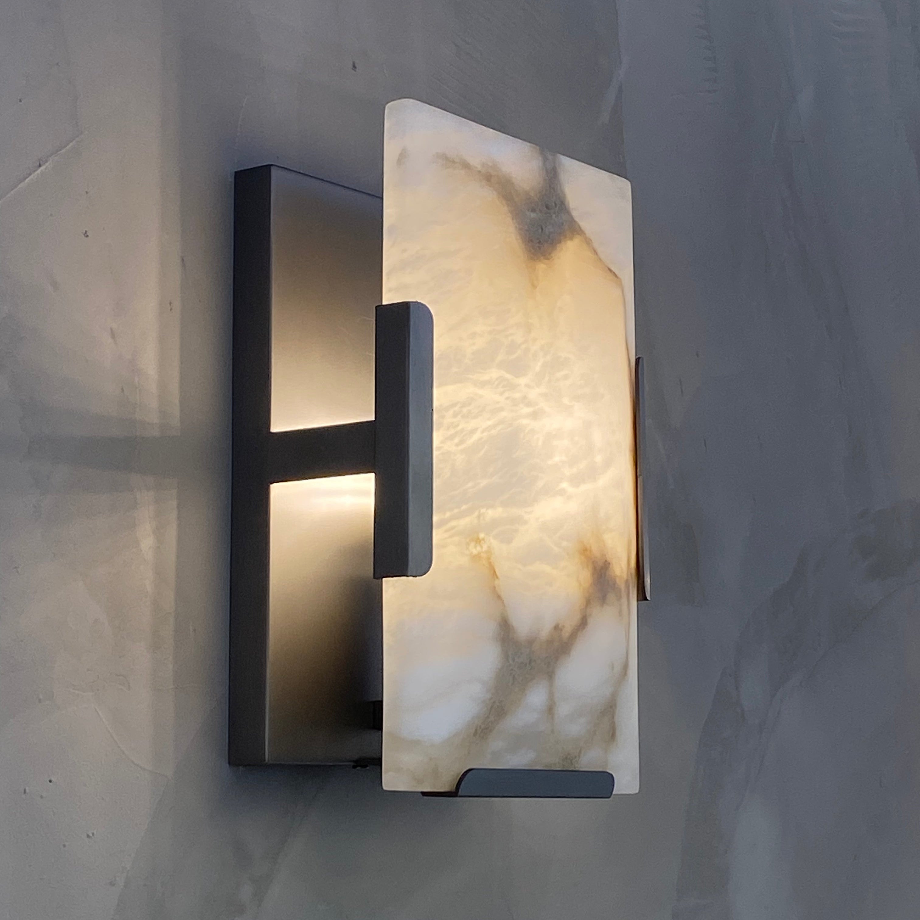 Side view of the Angel Wall Light showing its minimalist industrial frame and sculptural marble panel.