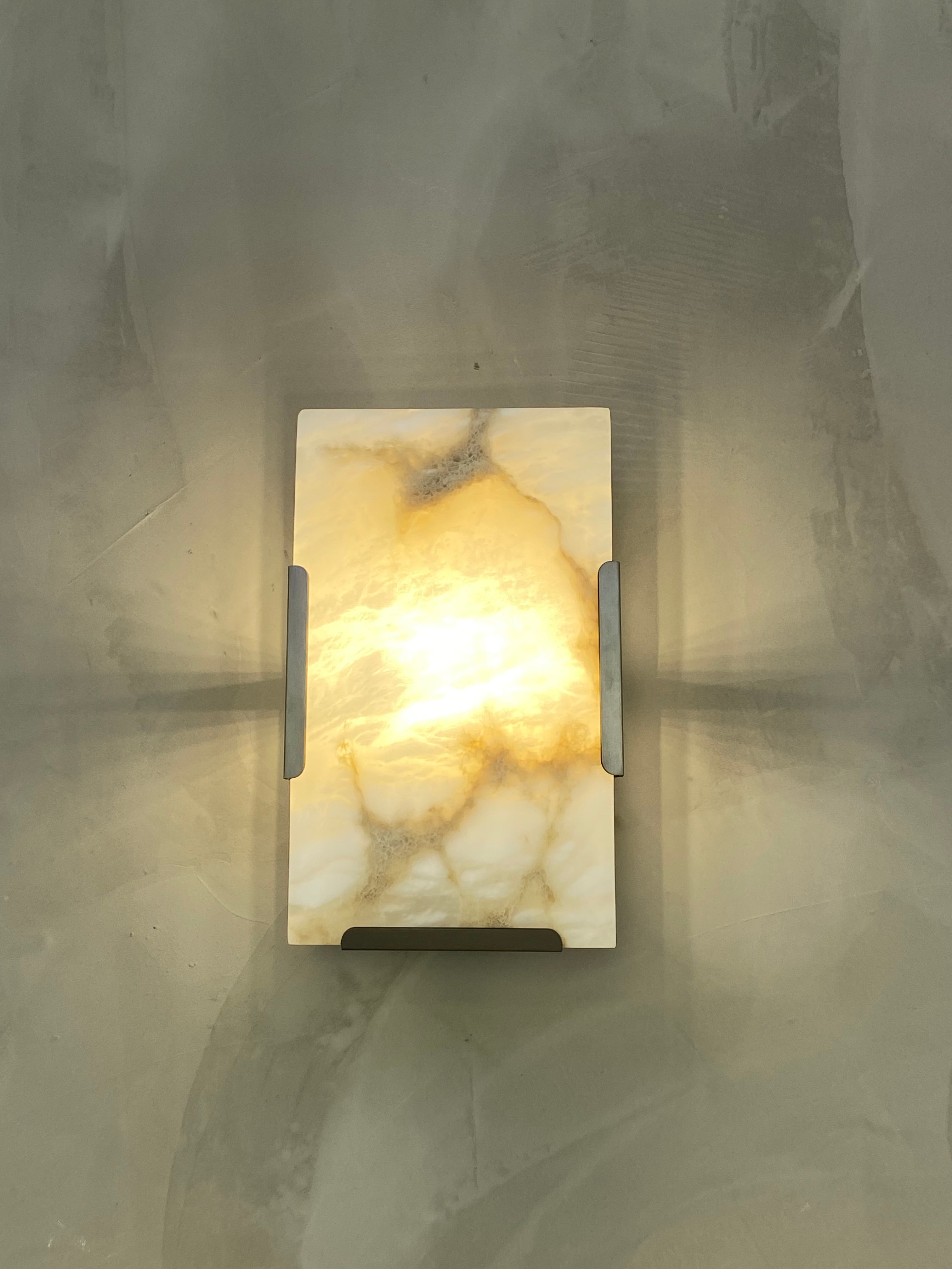 Angel Marble Wall Light illuminated warmly, highlighting its natural marble veining and refined structure.