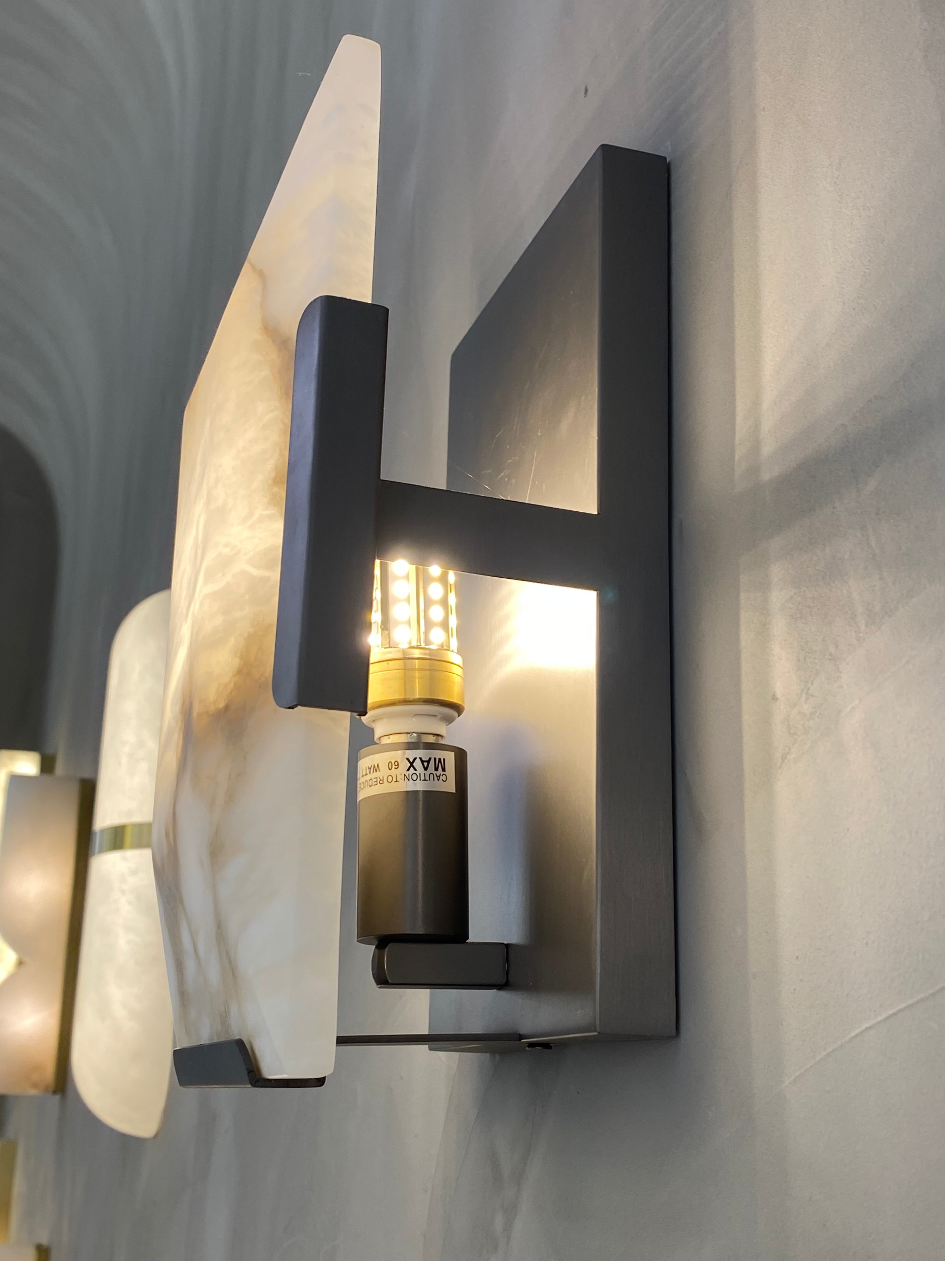 Upward angled view of the Angel Wall Light displaying marble textures and modern framing against a neutral wall.