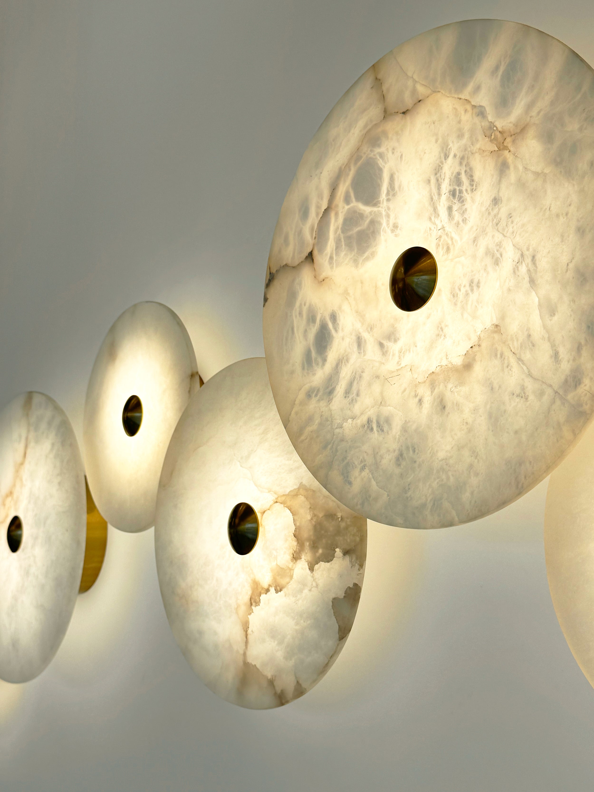 Close-up of a single Aria marble wall light glowing from its centre brass point.