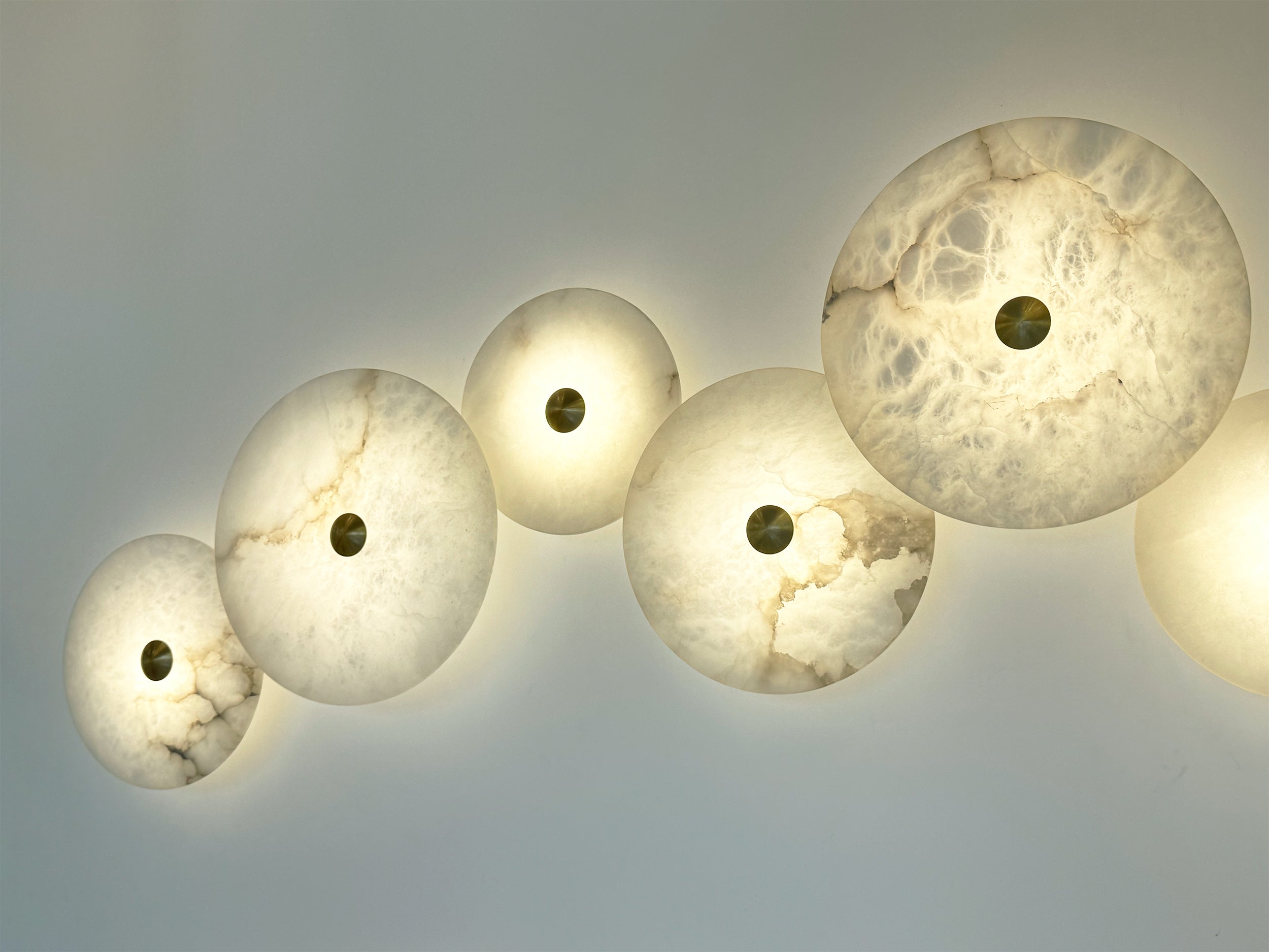 Detailed view of the Aria marble lights with central brass accents and diffused illumination.
