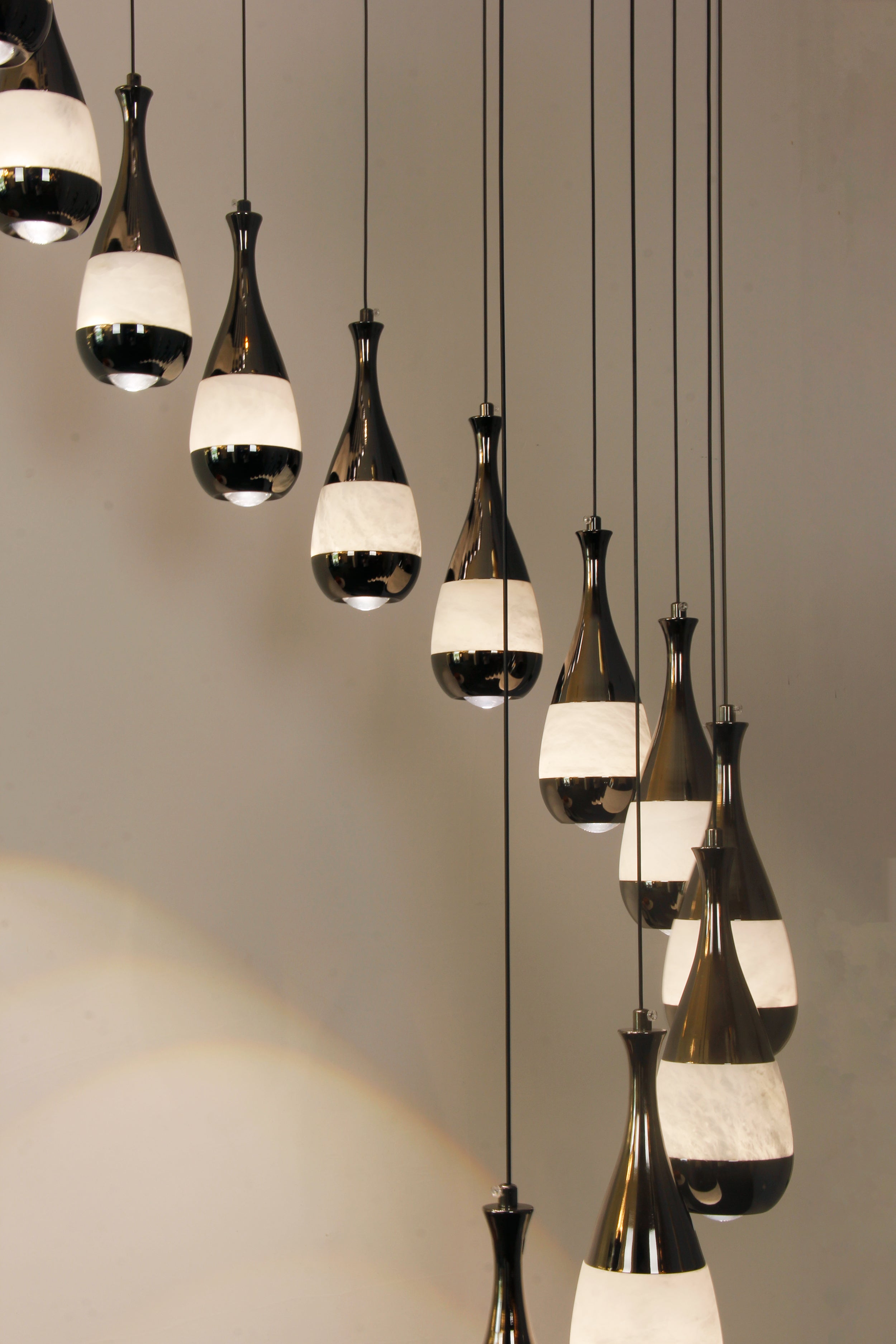 Side angle of the Armonia Marble Staircase Chandelier showing balanced spiral pendant flow.