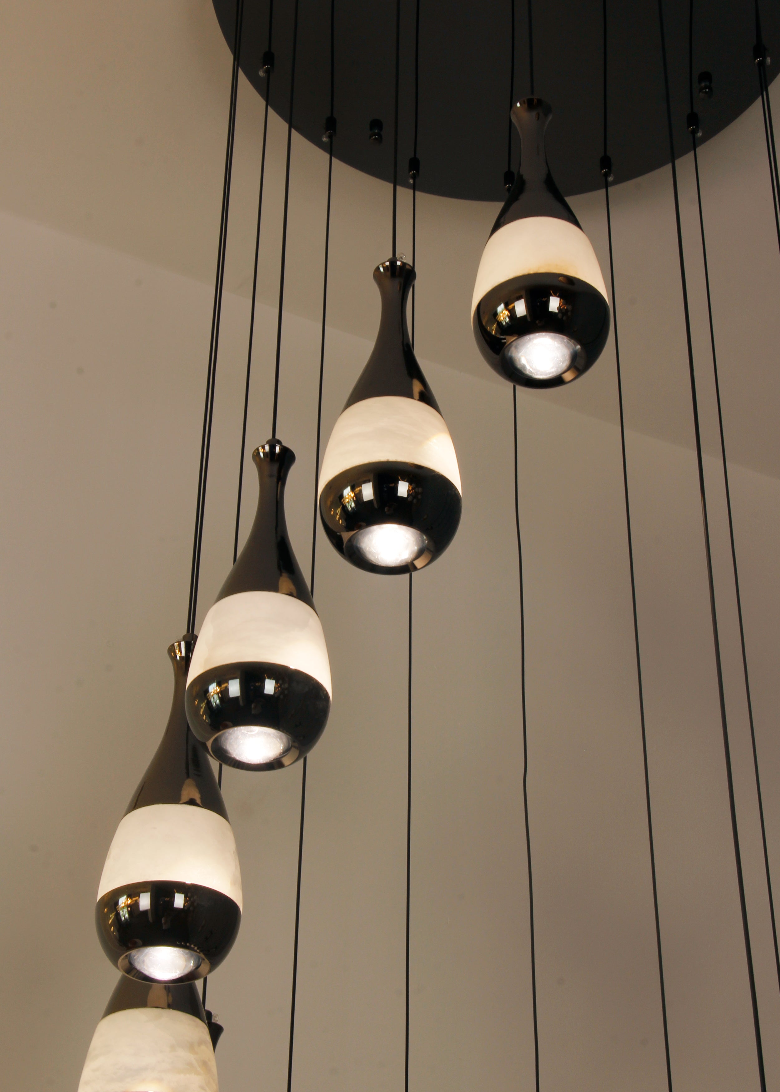 Detail of black ceiling plate and fine cables supporting the Armonia chandelier’s marble pendants.