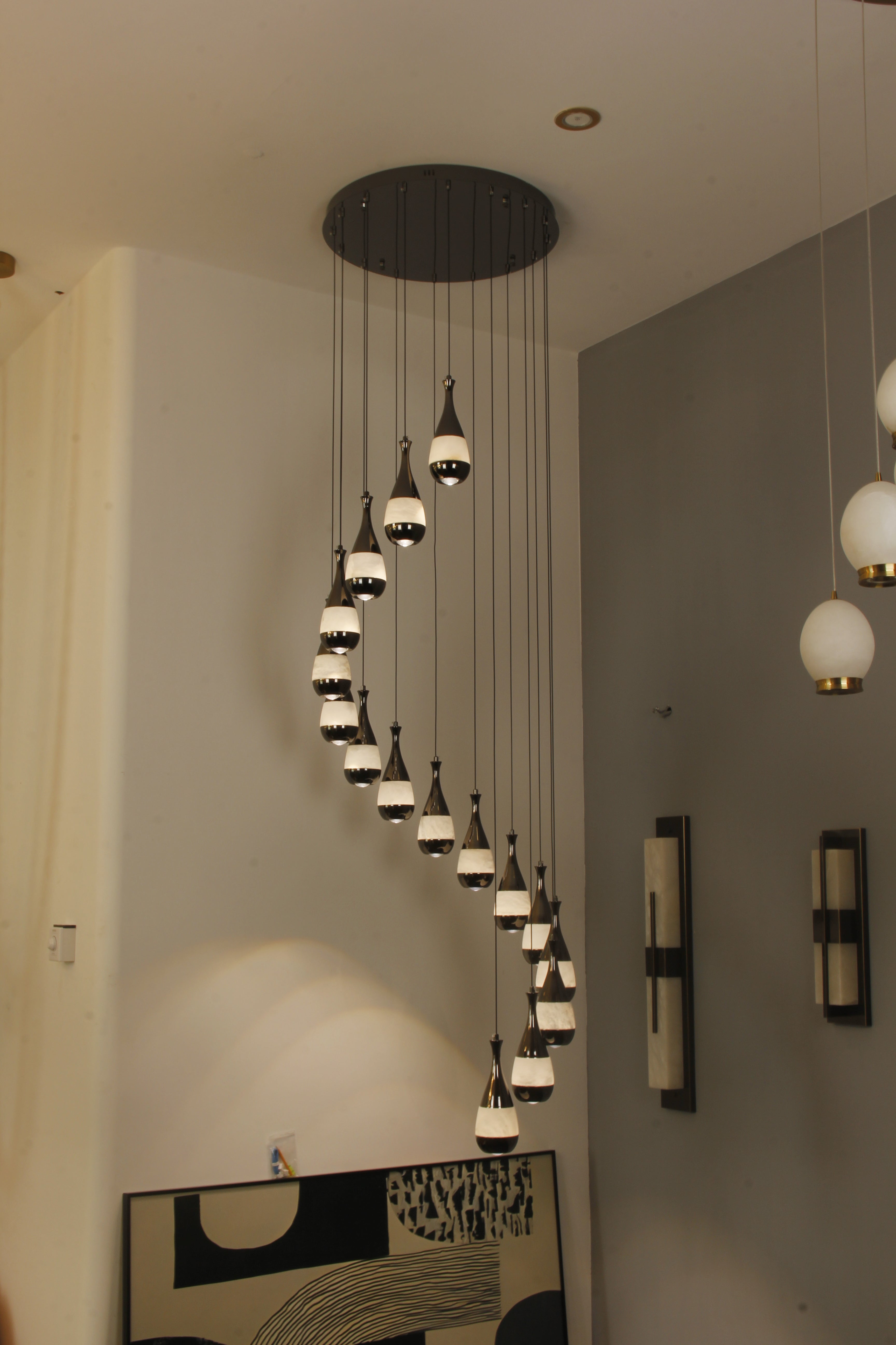 Decorative staircase chandelier with warm marble lights suspended in a spiral form.
