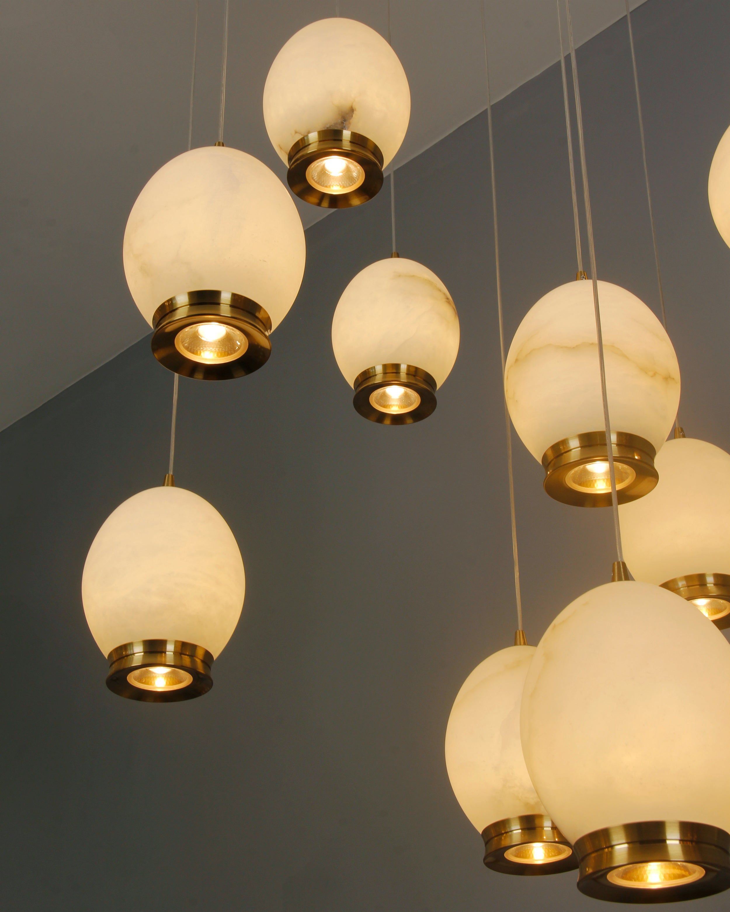 Close-up cluster of Caledonia marble pendant globes arranged at varying heights, creating a warm ambient glow.