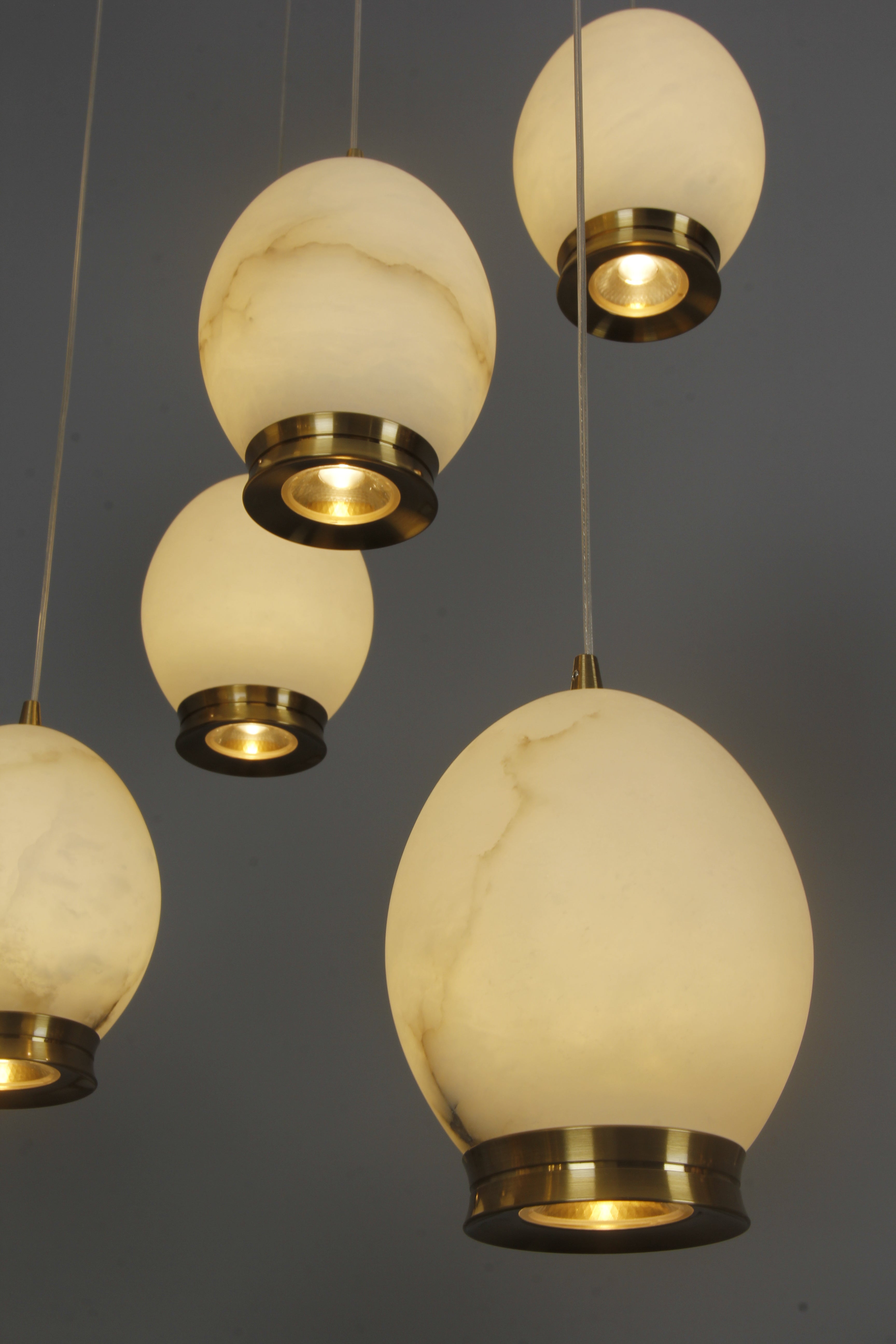 Angled detail of Caledonia chandelier marble globes highlighting refined brass accents and elegant suspension.