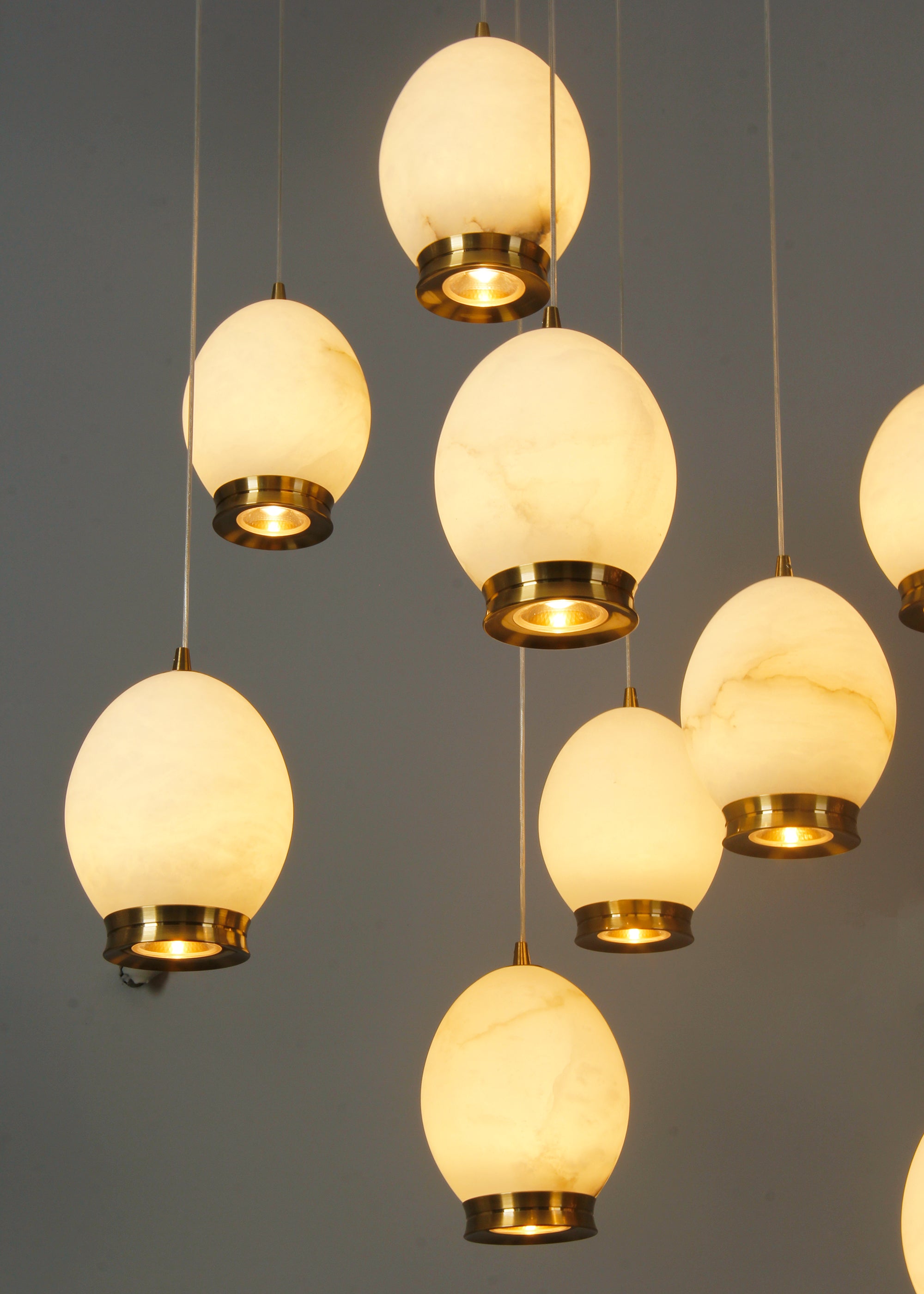 Caledonia staircase chandelier featuring softly illuminated marble globes suspended in a cascading formation.