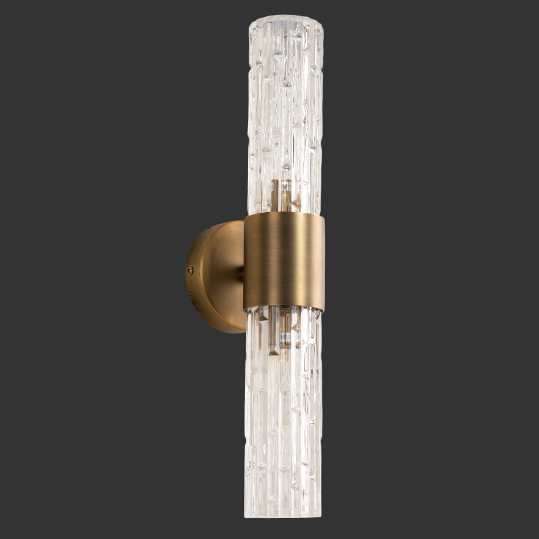 Wall-mounted light fixture with gold finish and clear glass on a gray background