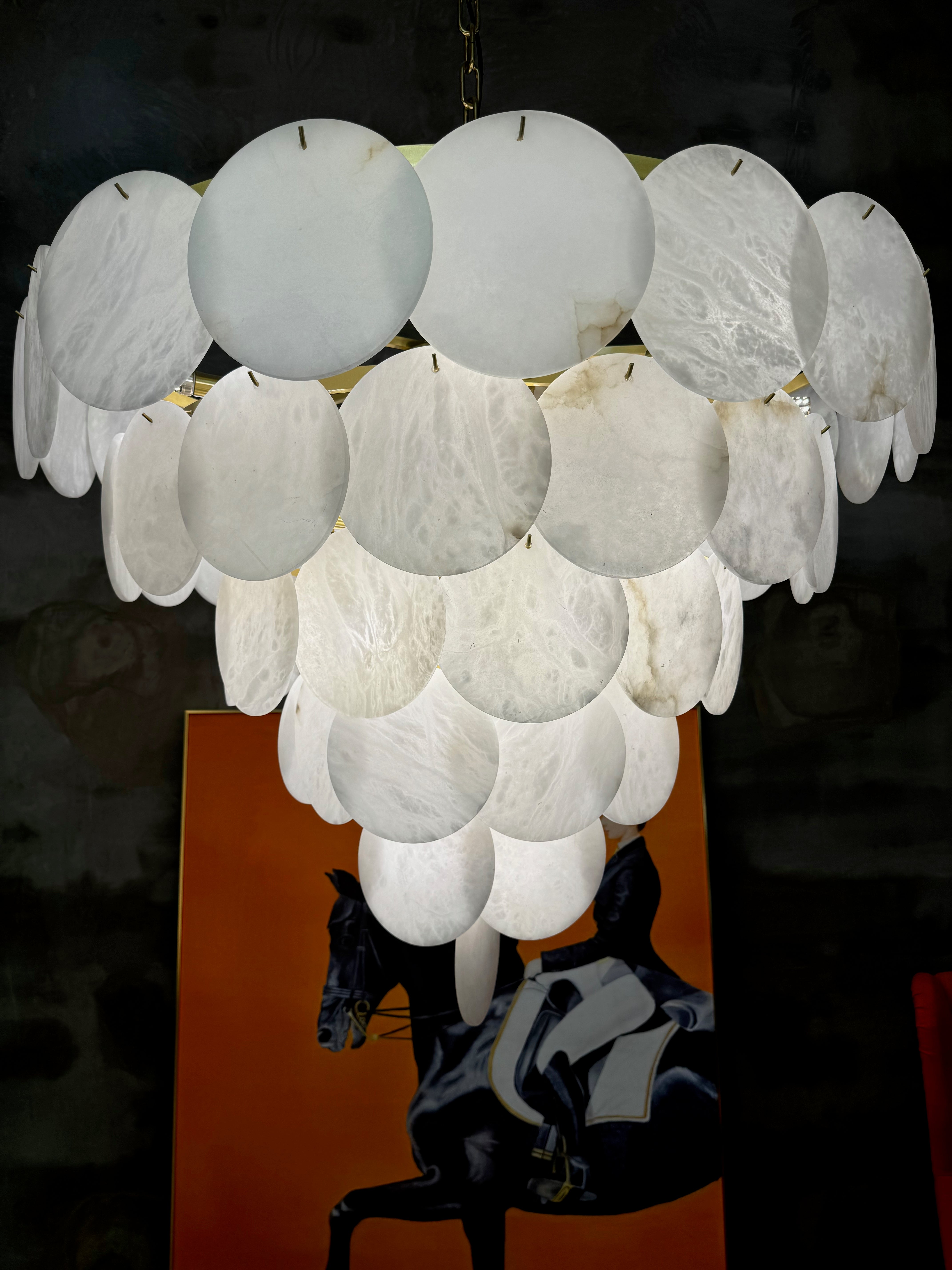 The Alfonso circular marble chandelier floating elegantly, diffusing a soft, warm glow perfect for high-end dining spaces.
