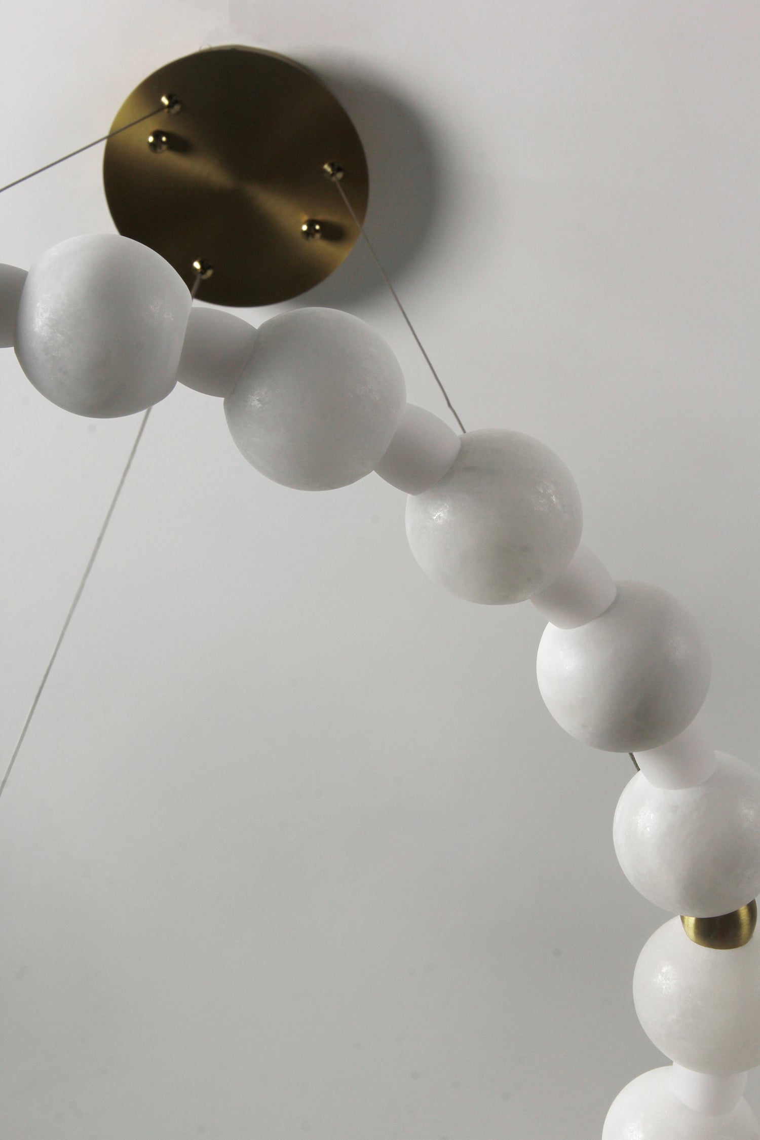 Close-up of Orbella circular chandelier showing smooth marble spheres and soft illumination.