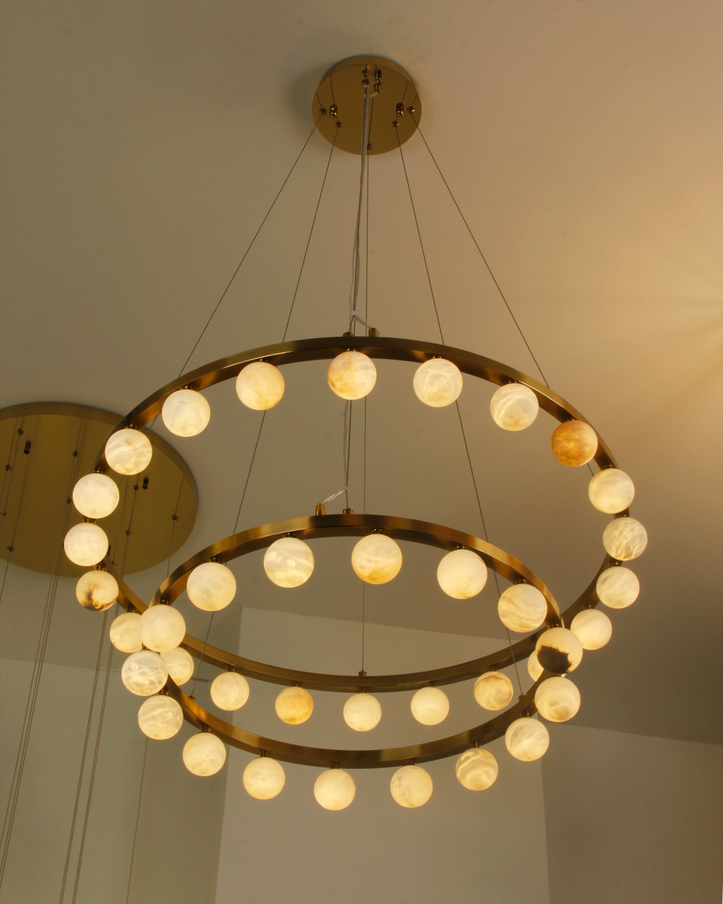 Orbit Marble Double Ring Chandelier illuminating a luxury modern interior design.