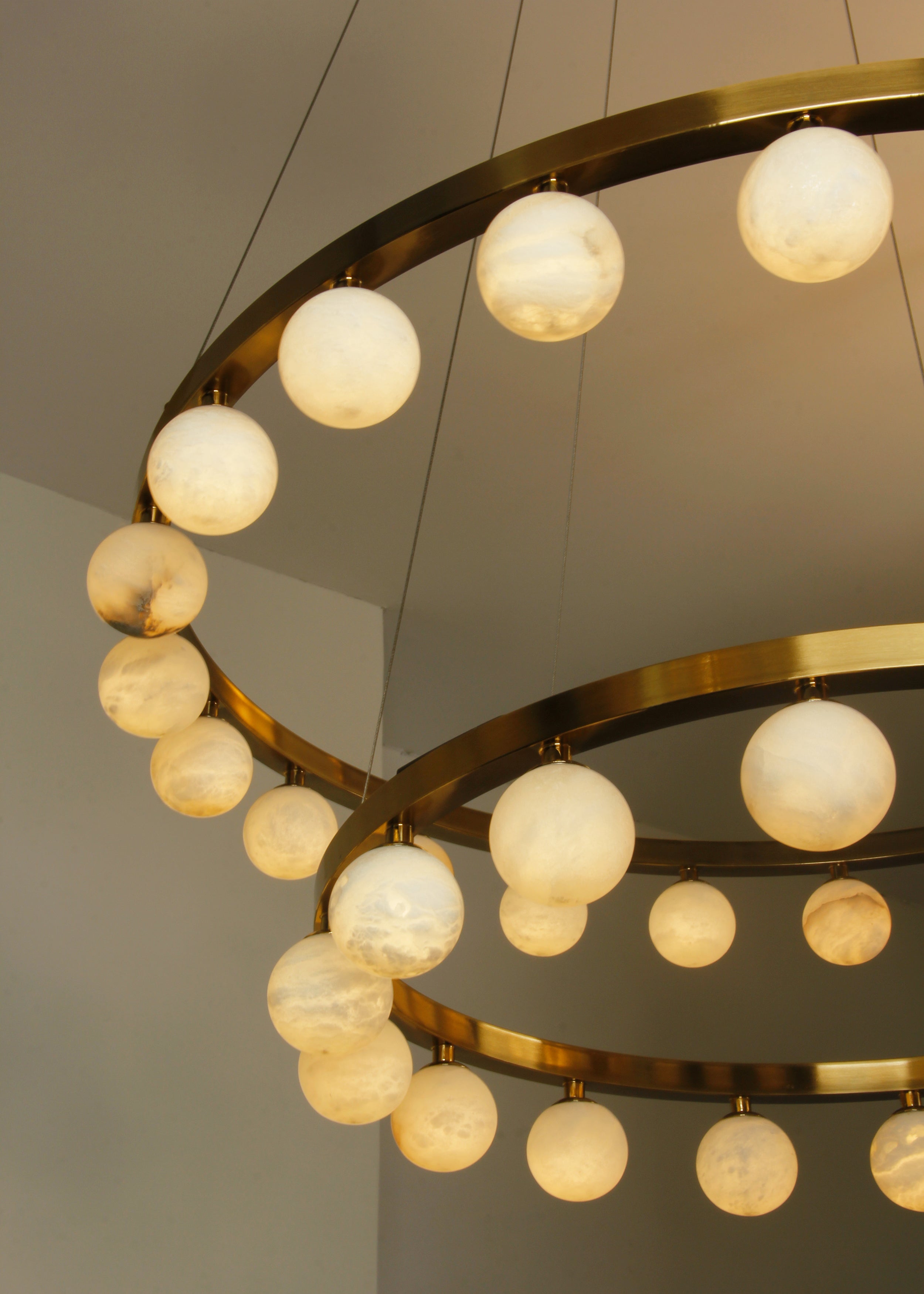 Close-up of Orbit Chandelier showing two tiers of natural white marble spheres and gold frame.