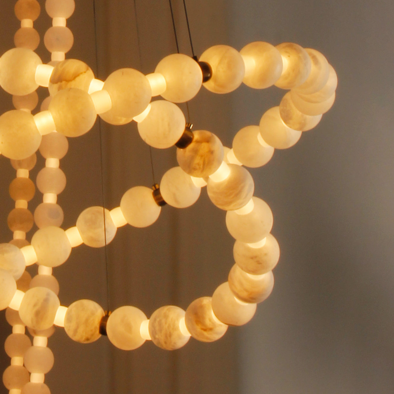 Close-up of Orbella Double Ring Chandelier showing intricate arrangement of luminous marble spheres.