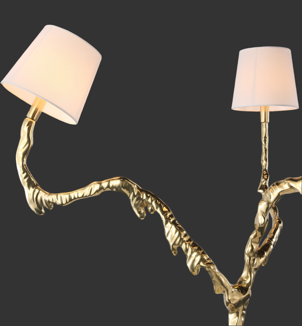 A beautifully styled high-end interior vignette featuring the sculptural gold Arboris floor lamp, creating a mood of refined luxury and sophistication.