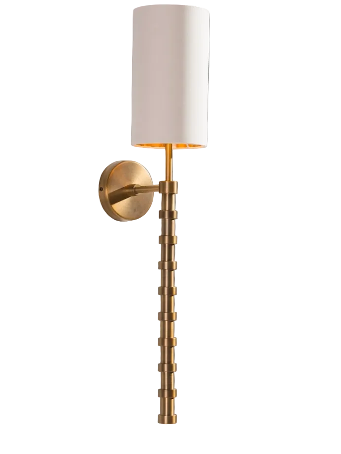 A close-up view of the Vorelli Orsini Wall Light, emphasizing the rich texture of its linear stem and the soft, ambient glow diffusing through the elegant fabric shade in a moody, upscale setting.