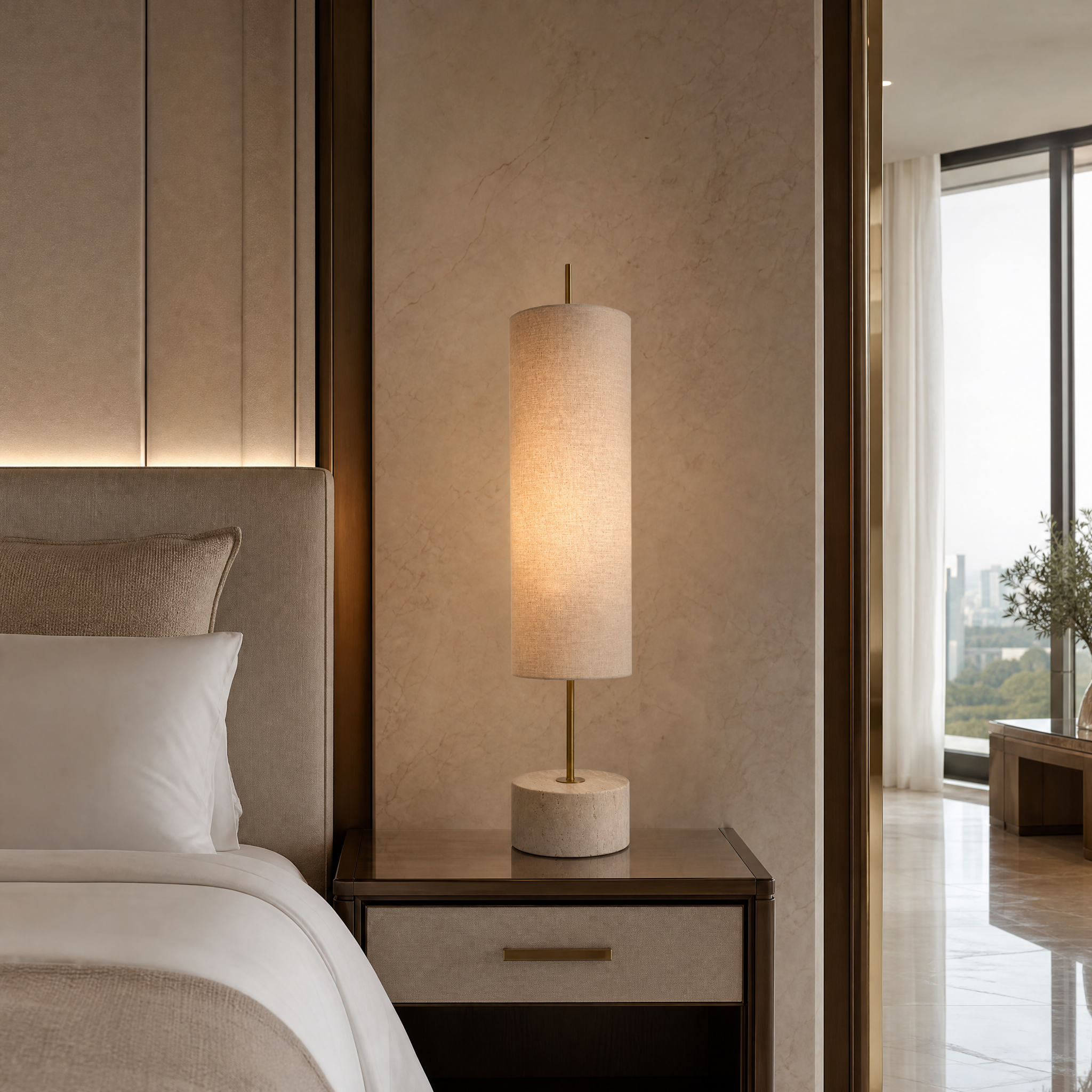 The Arvane brass and travertine table lamp by VORELLI casting a warm, sophisticated ambient glow in a high-end boutique hotel lobby.