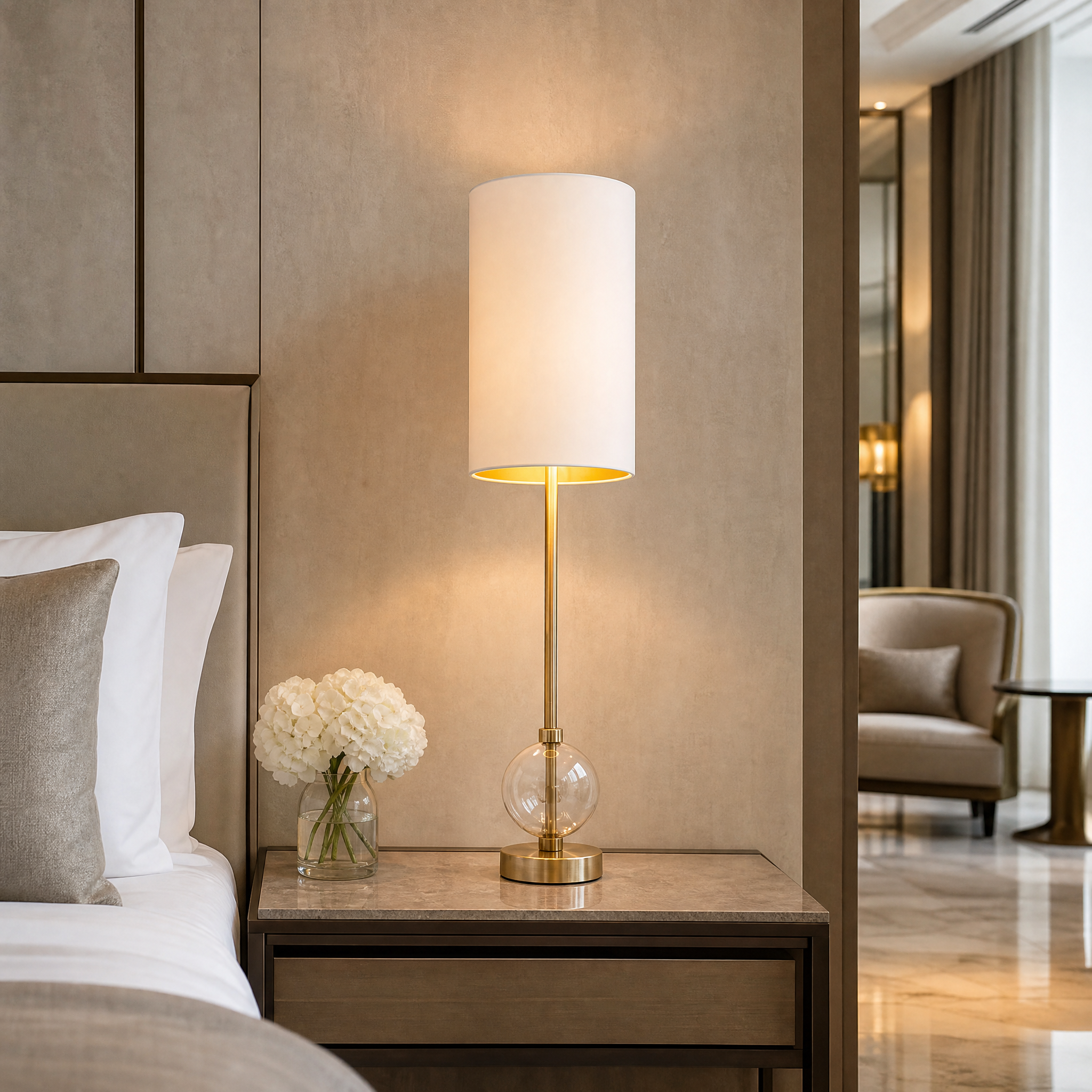 Sophisticated Aurezza table lamp with brass stem and crystal sphere base in a modern hotel suite bedside setting.
