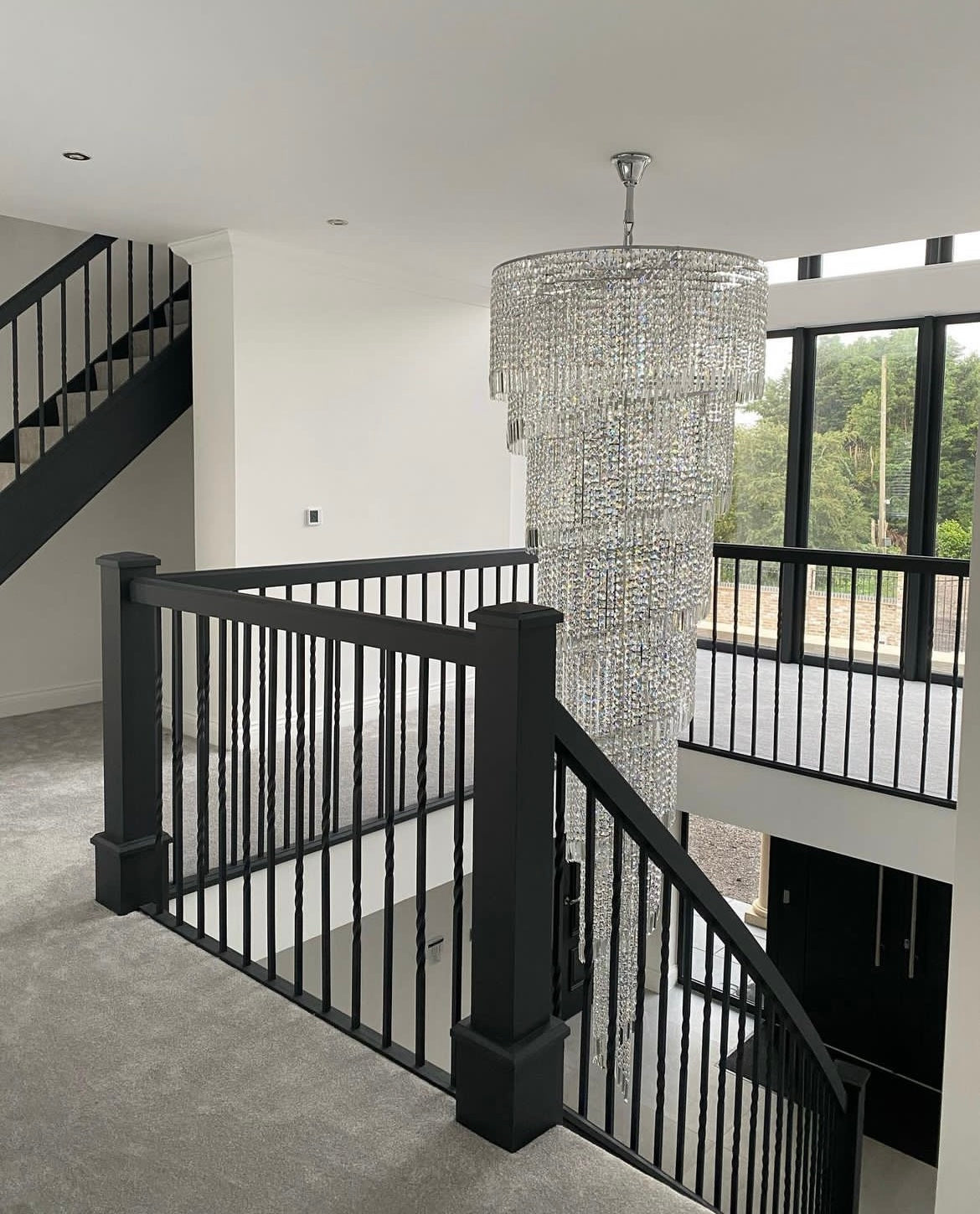 Full-length view of the Basilgio chandelier cascading through a white staircase setting.