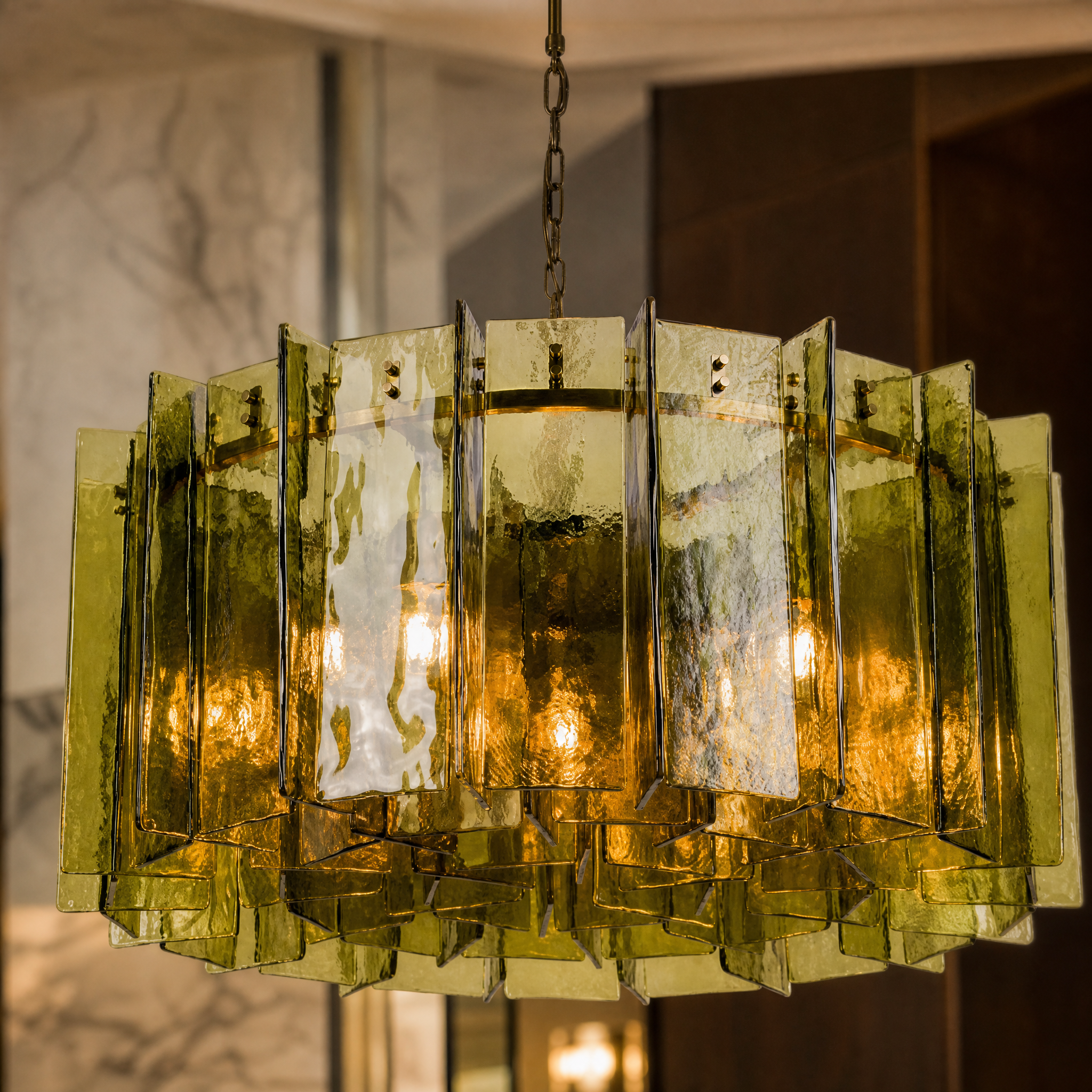 A detailed closeup of the Vorelli Berlinio chandelier, highlighting the individual bottle green glass polyhedrons bolted onto the premium brass frame.
