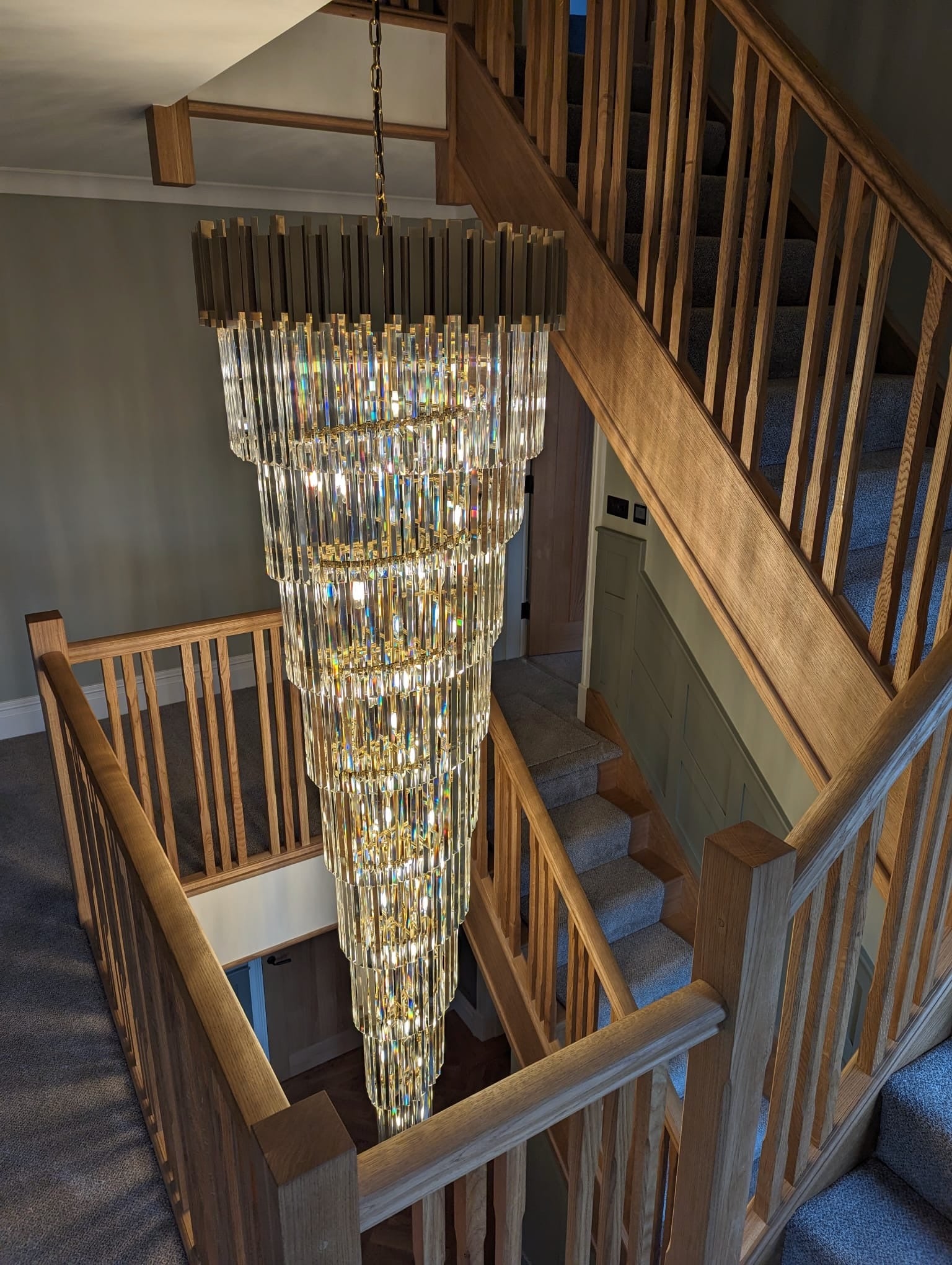 Luxury Boeotia spiral staircase chandelier cascading through a double-height stairwell with diamond cut crystal prisms