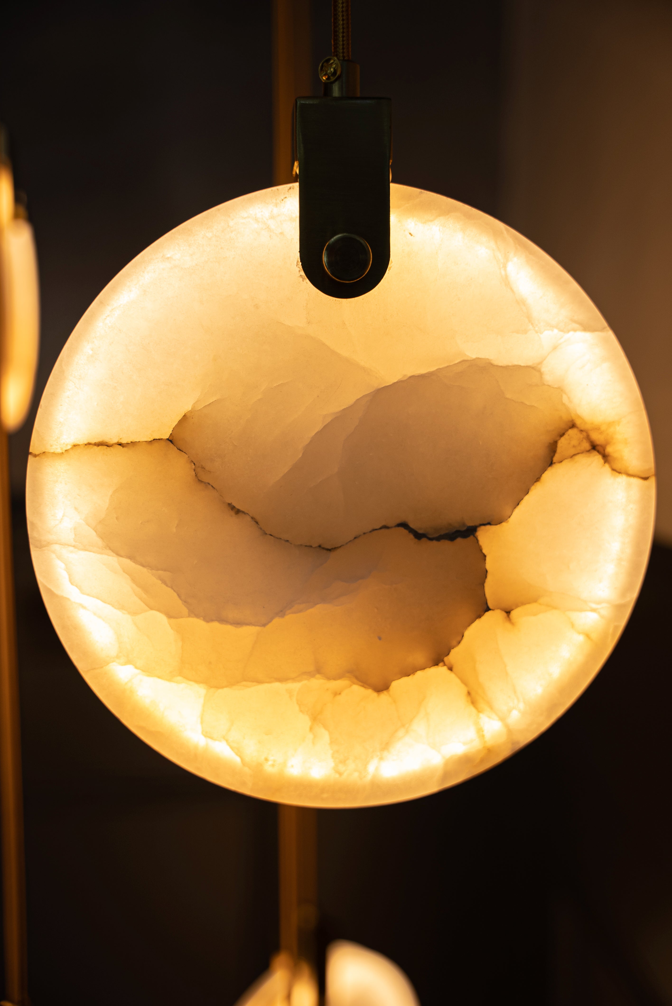 Close up of Calacatta marble disc detail on a luxury staircase chandelier.