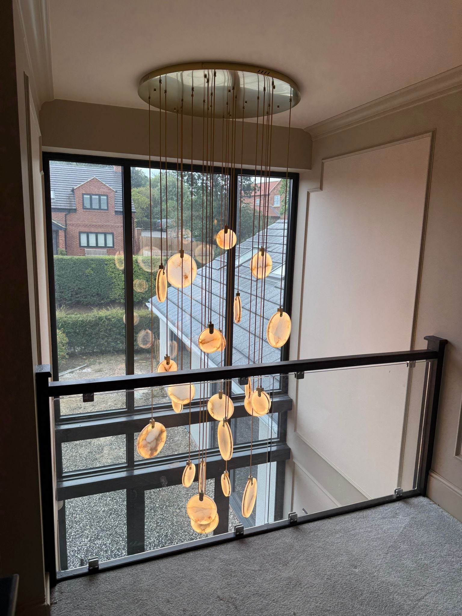 Calacatta marble staircase chandelier viewed from upper landing in a luxury double height interior.