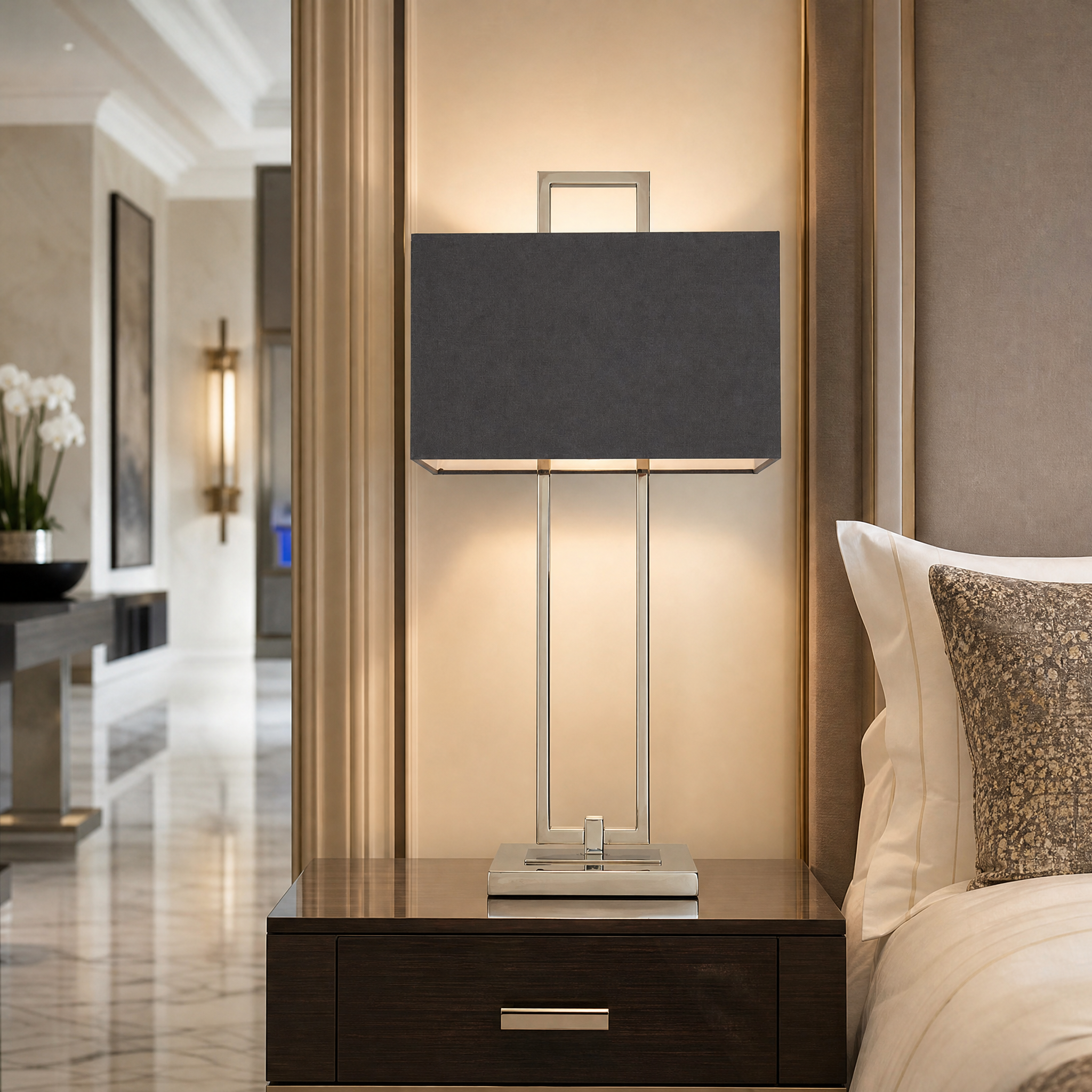 VORELLI Calvero nickel table lamp with dark fabric shade casting a warm ambient glow on a side table in a contemporary residential living room.