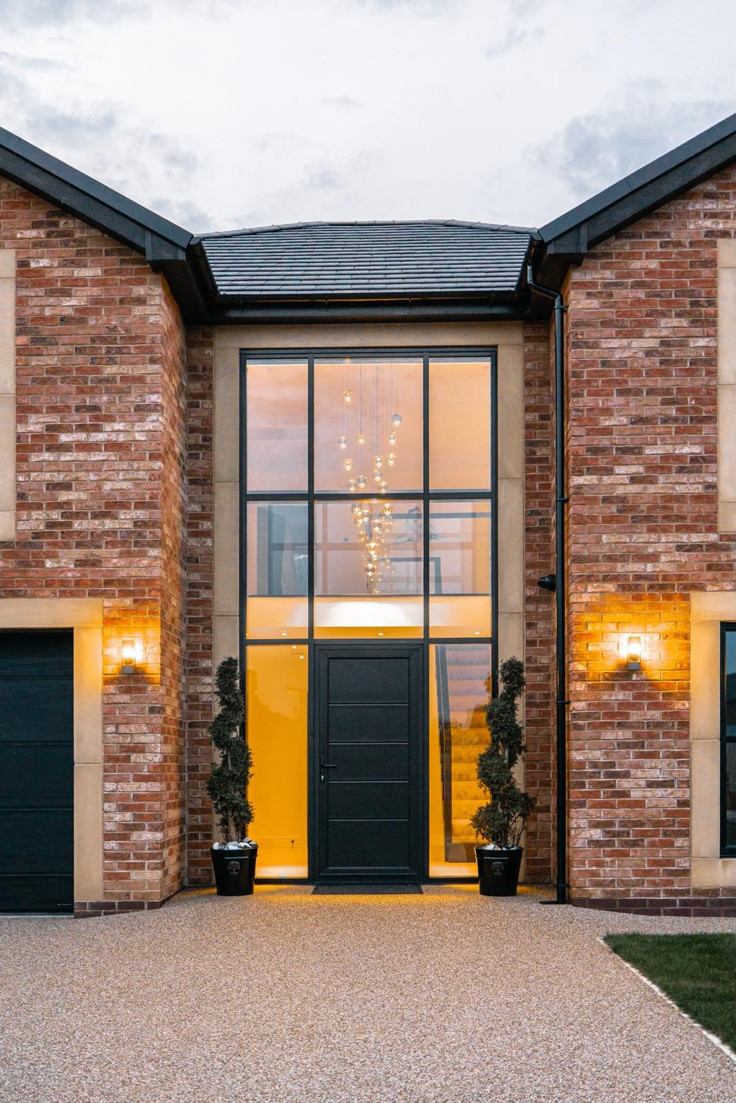 Carlito pendant staircase chandelier visible through a double-height front entrance in a luxury home