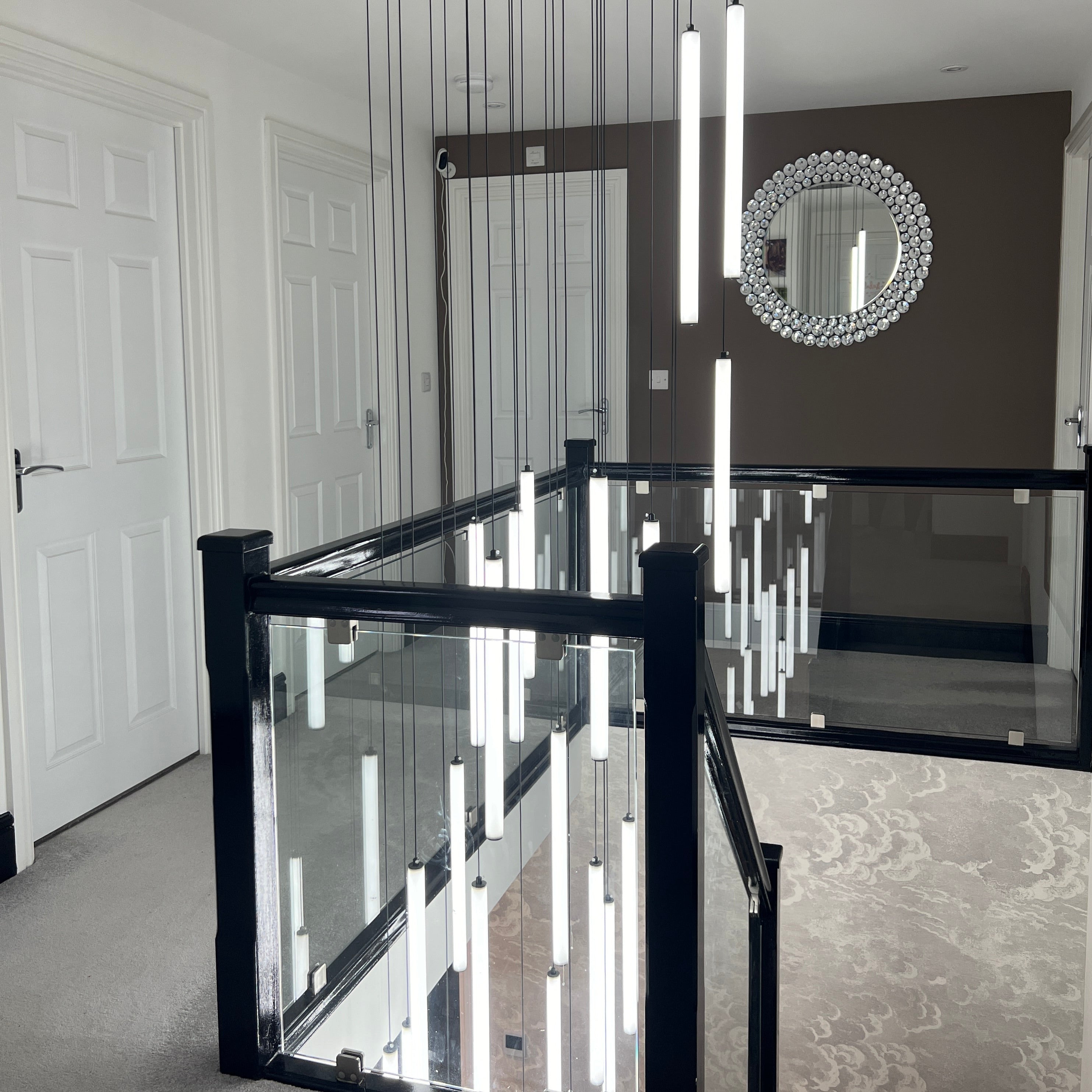 multiple cowley pendant lights suspended above staircase in contemporary interior