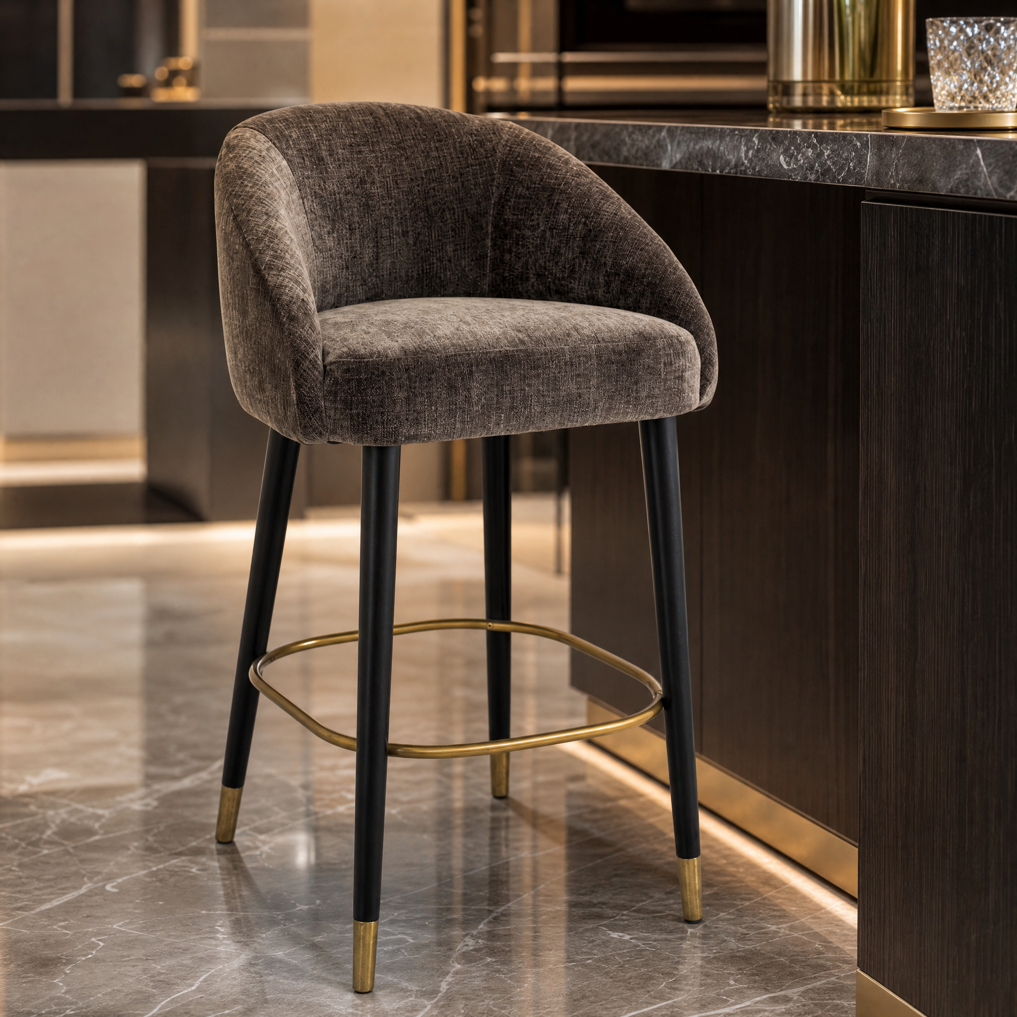 Macro detail shot of the Denevo counter stool showcasing the refined brass finish trim, smooth black frame, and premium mouse gray fabric texture.