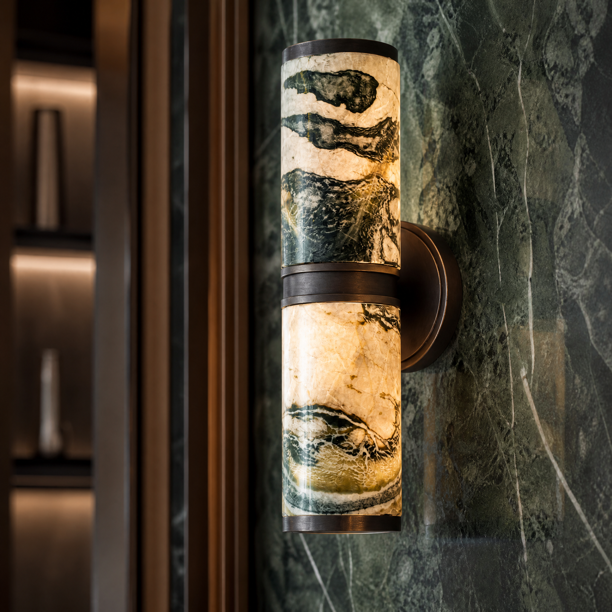 Detailed view of the natural rich green marble veins and warm antique brass accents on the VORELLI Almora wall light.