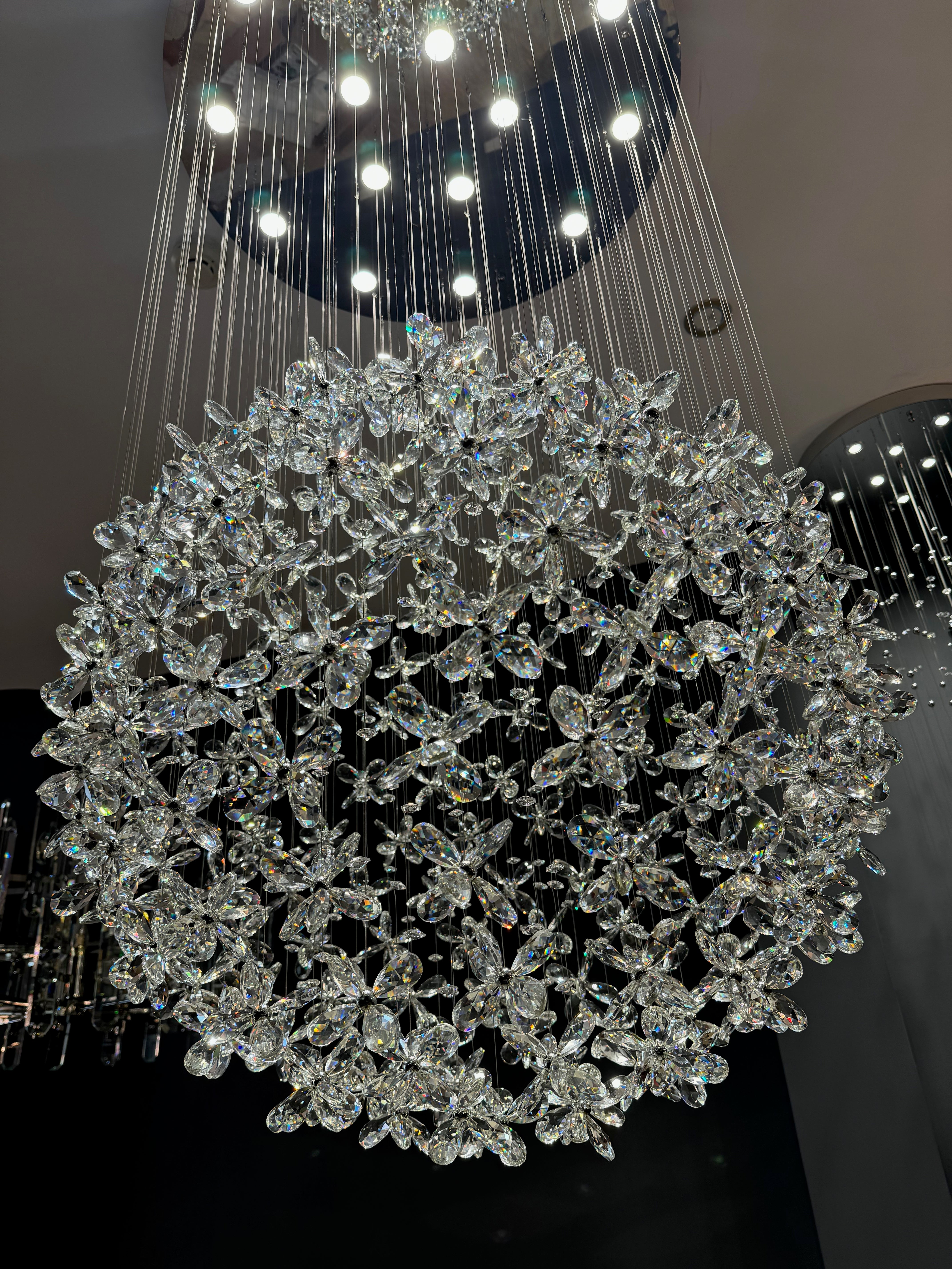 Diamond cut flower crystal staircase chandelier creating a dramatic spherical centrepiece