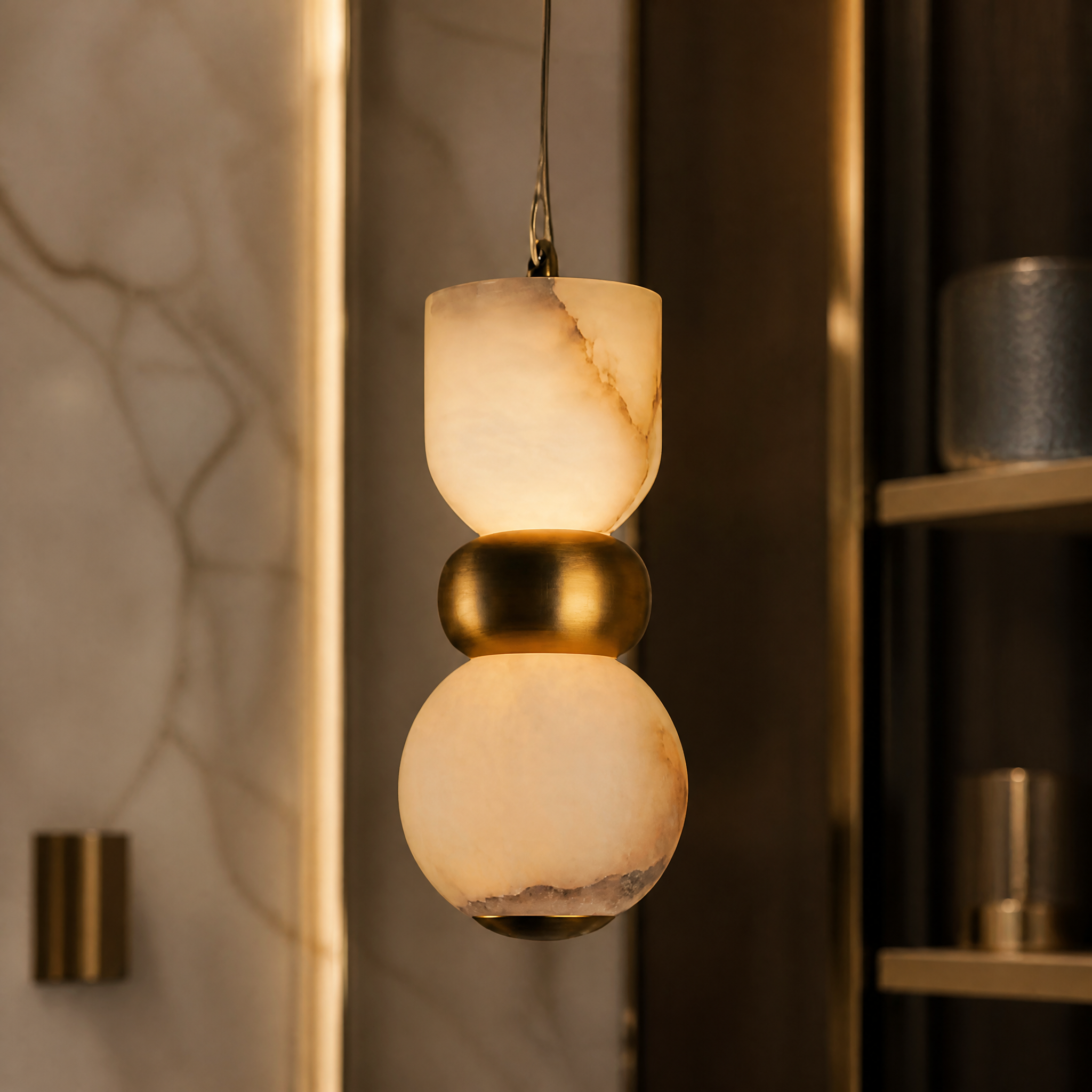 A detailed closeup of the Forma pendant light highlighting the sculptural natural marble textures and refined contemporary metallic finish.