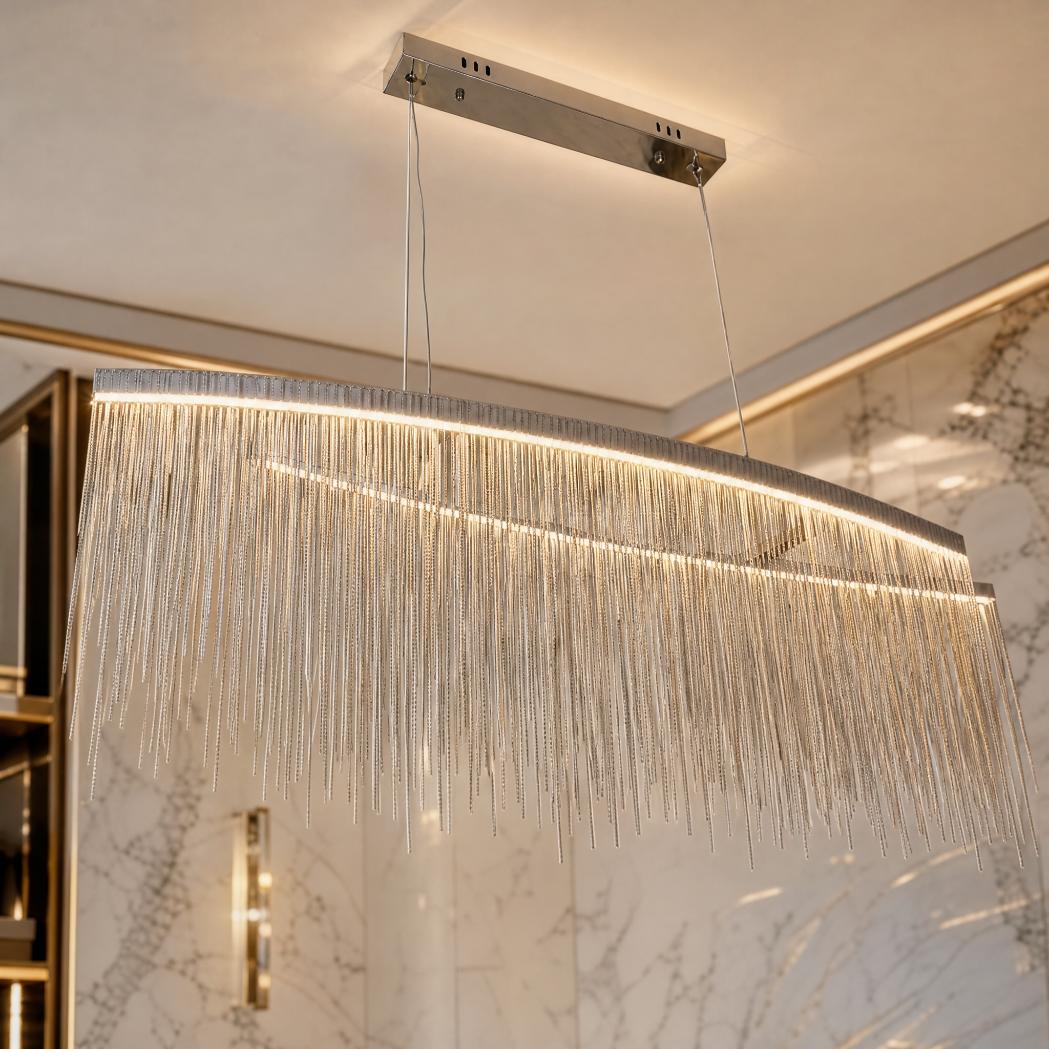 Glamorous ambient mood lighting from the VORELLI Adlington Arc Chandelier highlighting its premium metal finish and cascading chains.