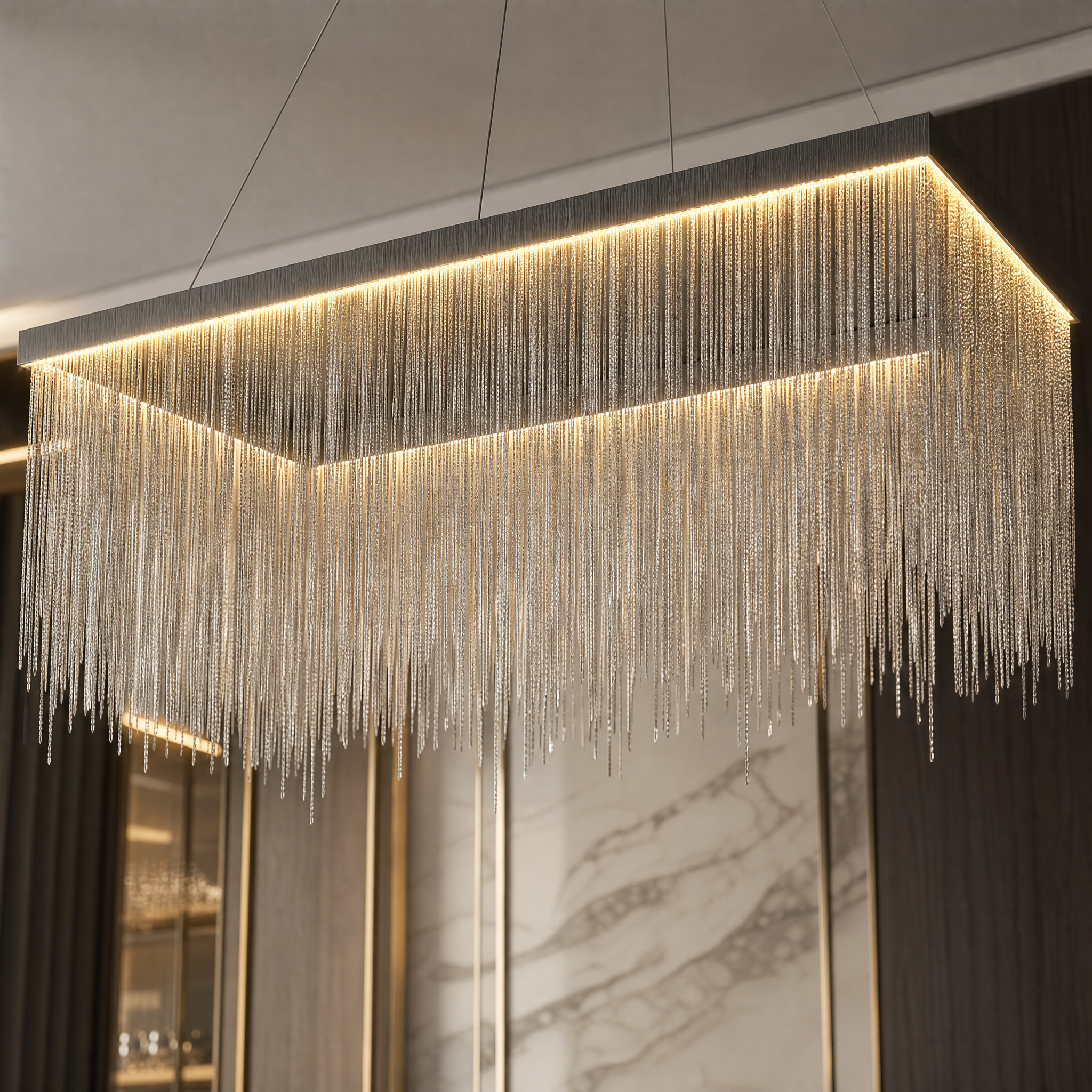 Glamorous mood lighting reflecting through the cascading metal chains of the VORELLI Adlington rectangular chandelier.