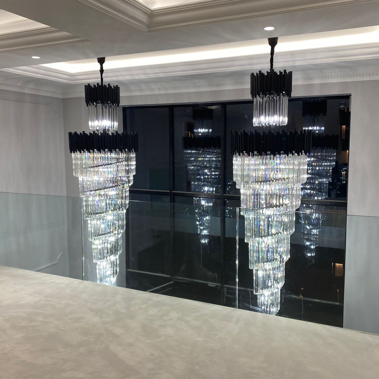 Modern crystal staircase chandelier reflected against glass balustrade