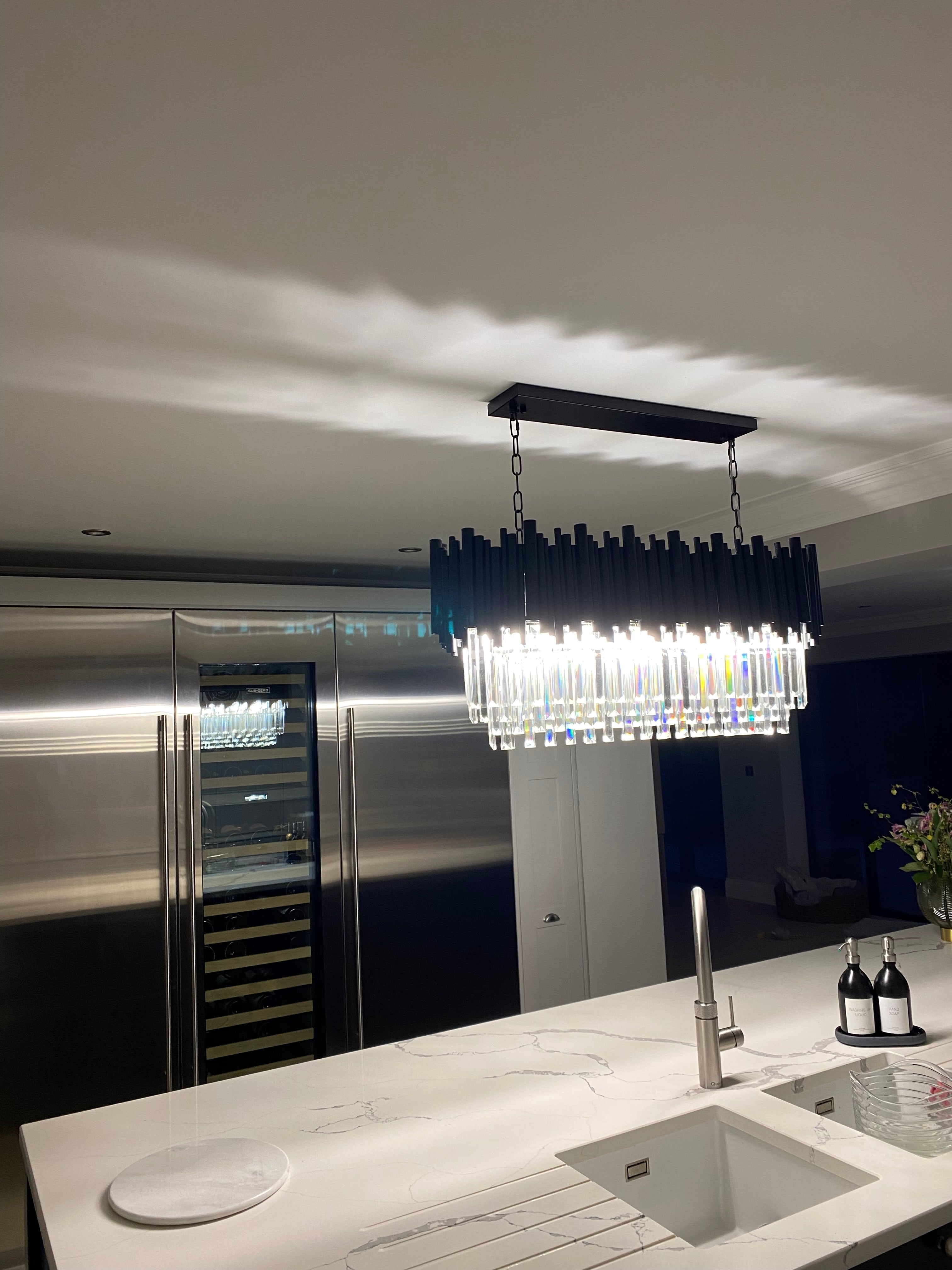 VORELLI® Gotham Rectangular Chandelier above a modern kitchen island with diamond cut crystal bars and architectural lighting design
