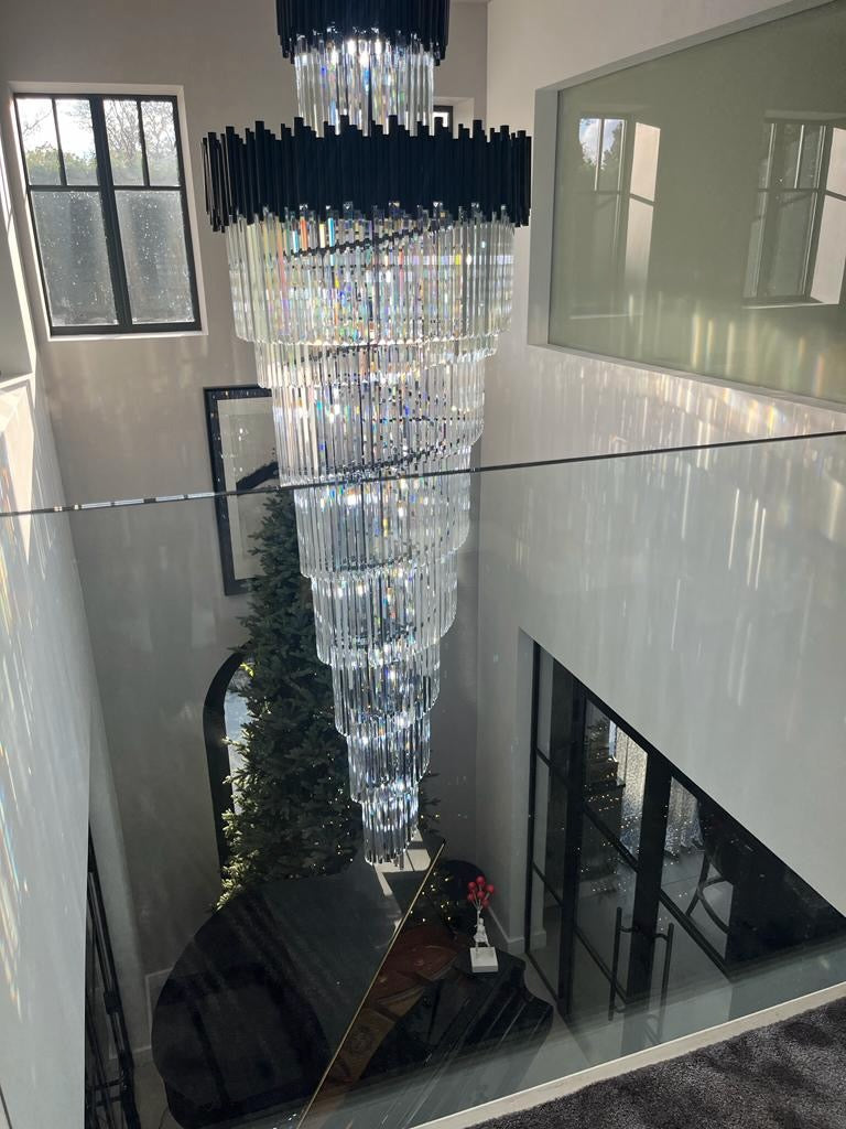 Extra long tiered crystal staircase chandelier cascading through a double height luxury landing