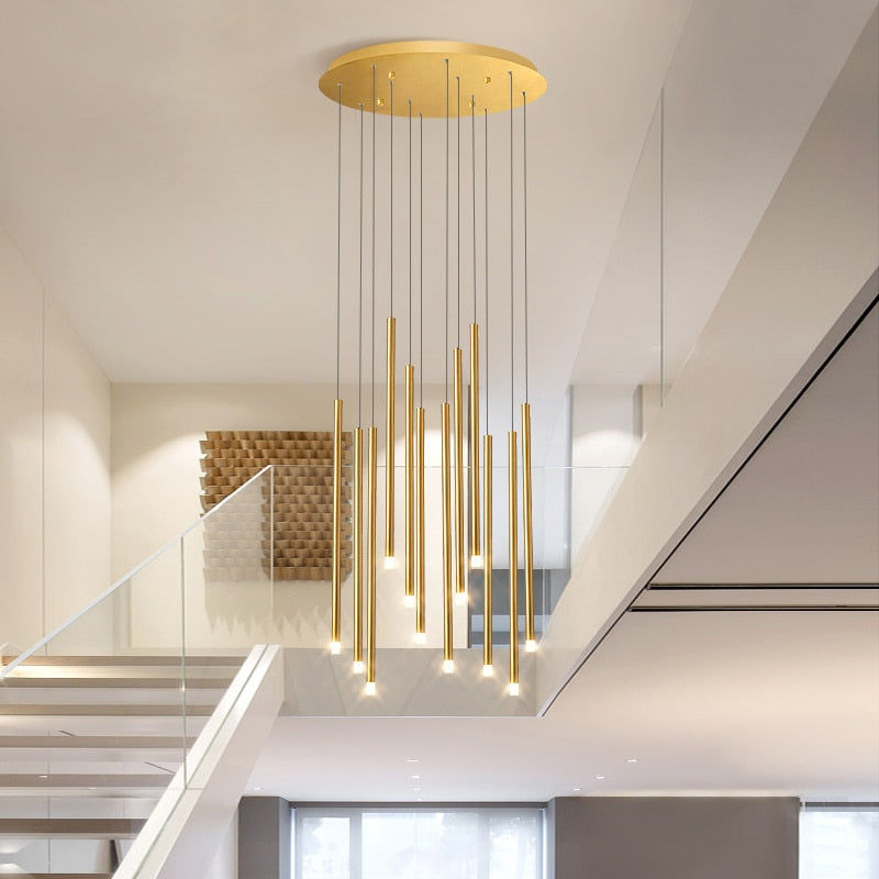 Cylinder pendant staircase chandelier in warm gold finish creating elegant vertical illumination