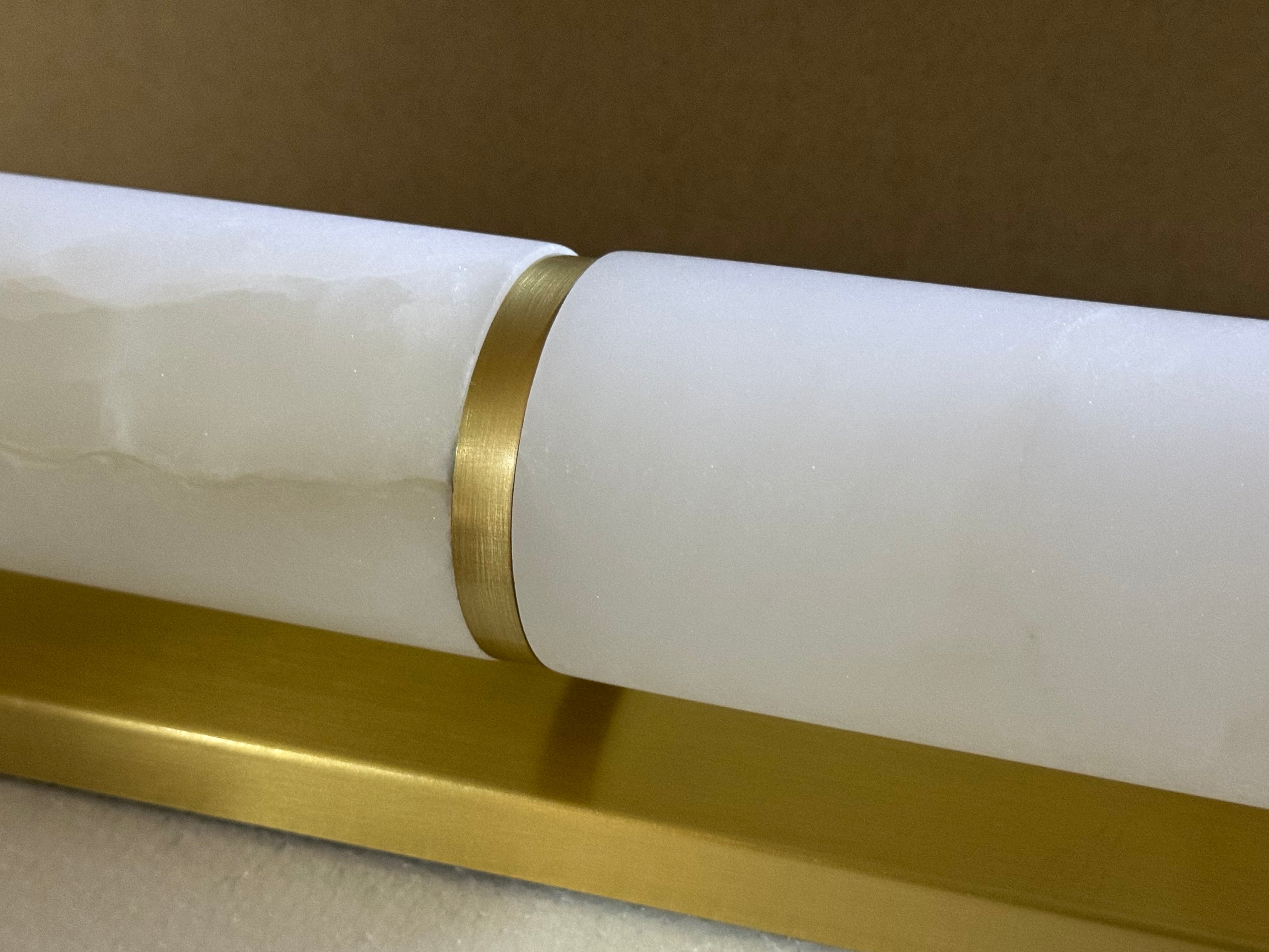 Close-up of illuminated natural marble and gold metal finish on the Lucente luxury wall light