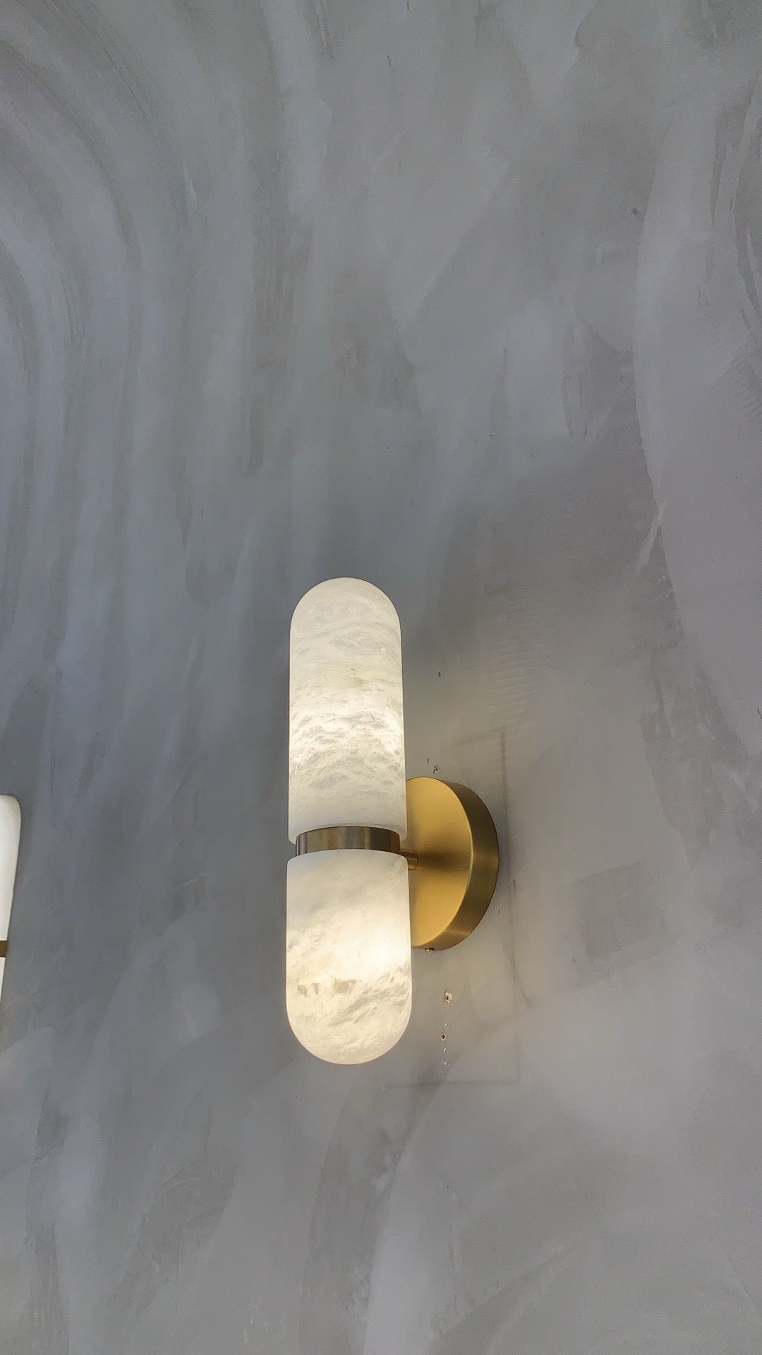 Luma marble wall light glowing softly in a dim luxury interior setting