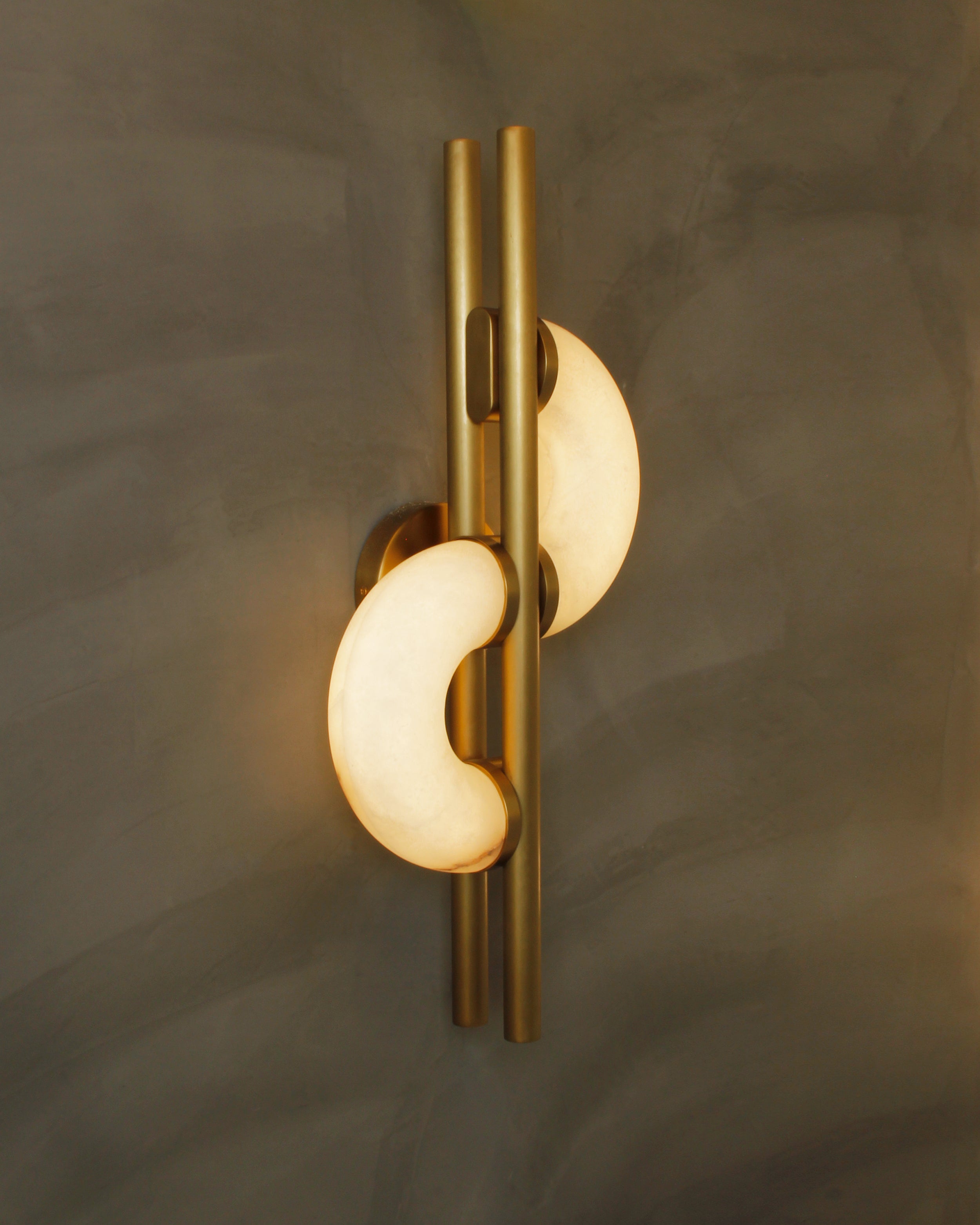 Front view of Lunaro marble wall light showing crescent marble elements and brass structure