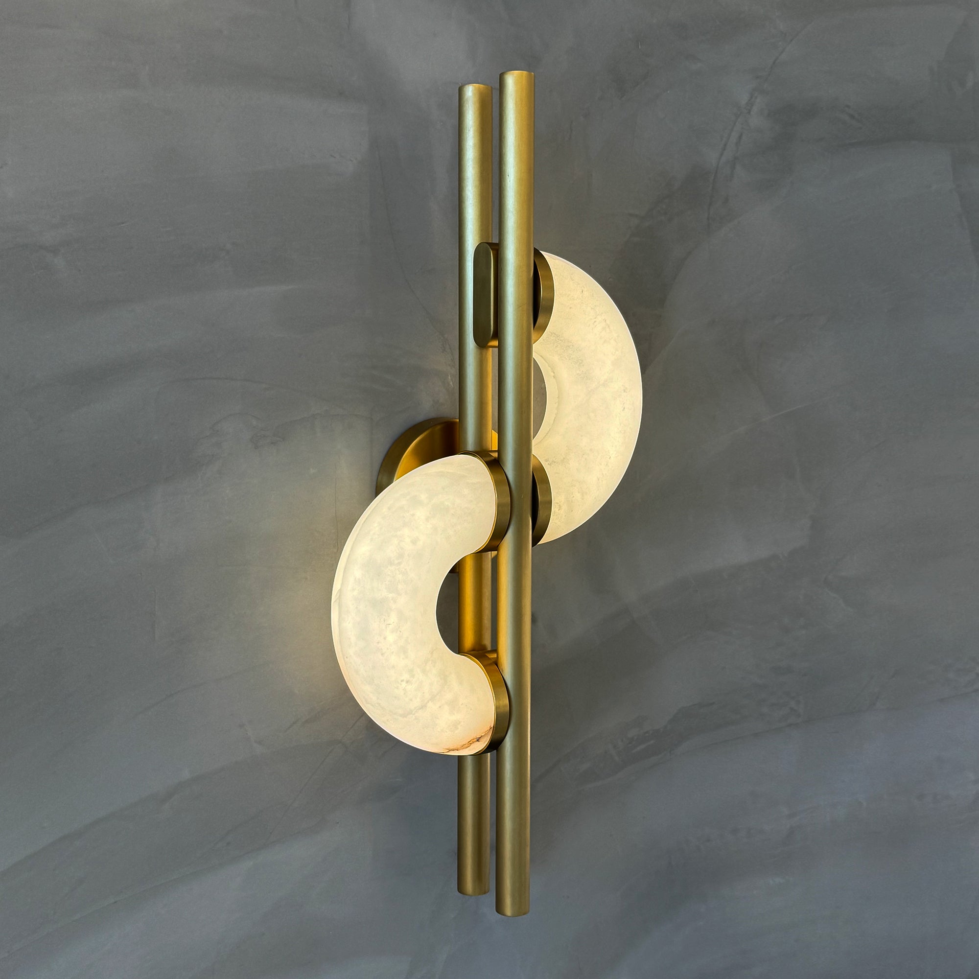 Twin crescent marble Lunaro wall light mounted on a grey wall with warm ambient glow