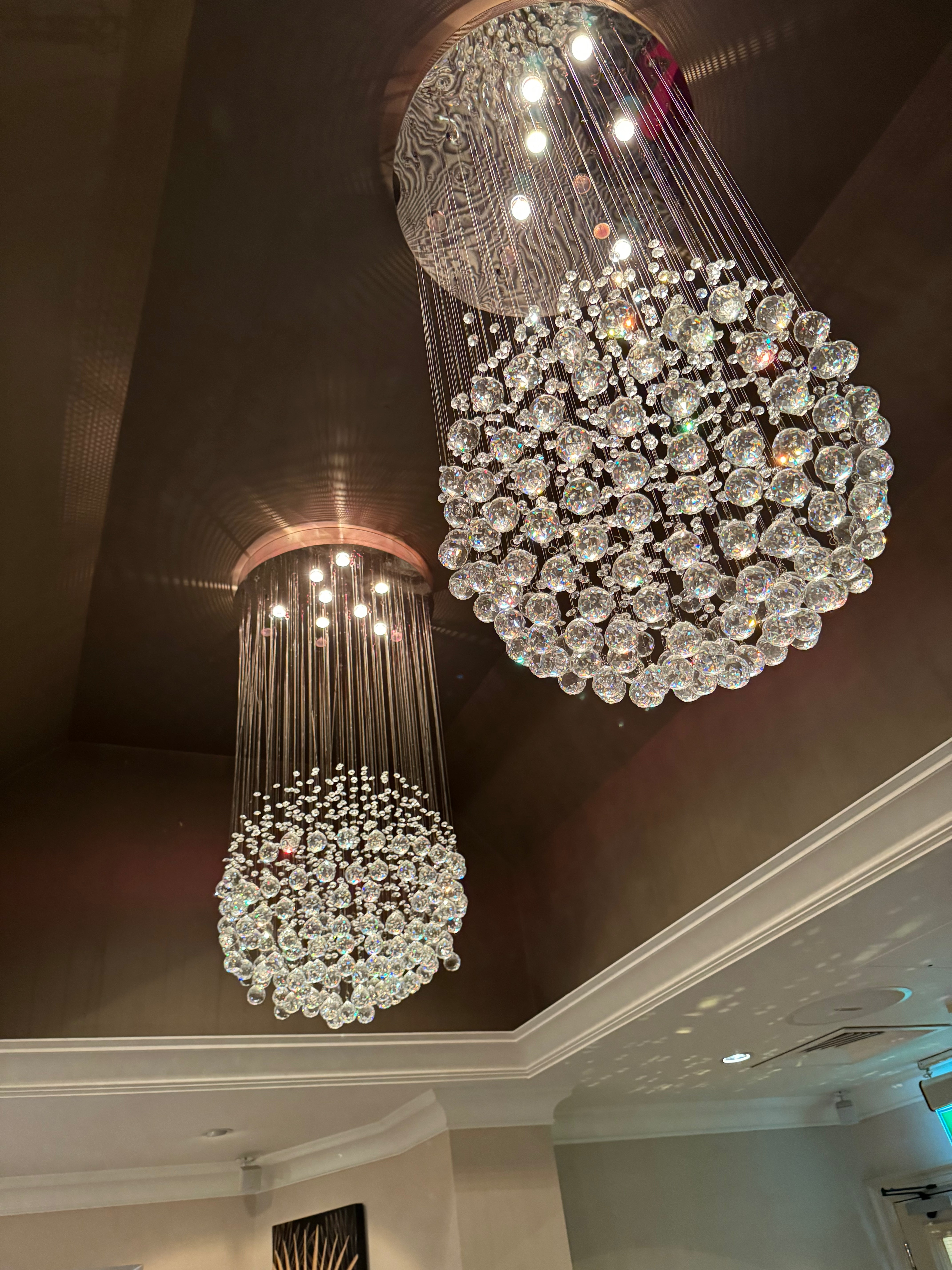 Whirlow crystal staircase chandelier installed in a tall stairwell with cascading crystal sphere