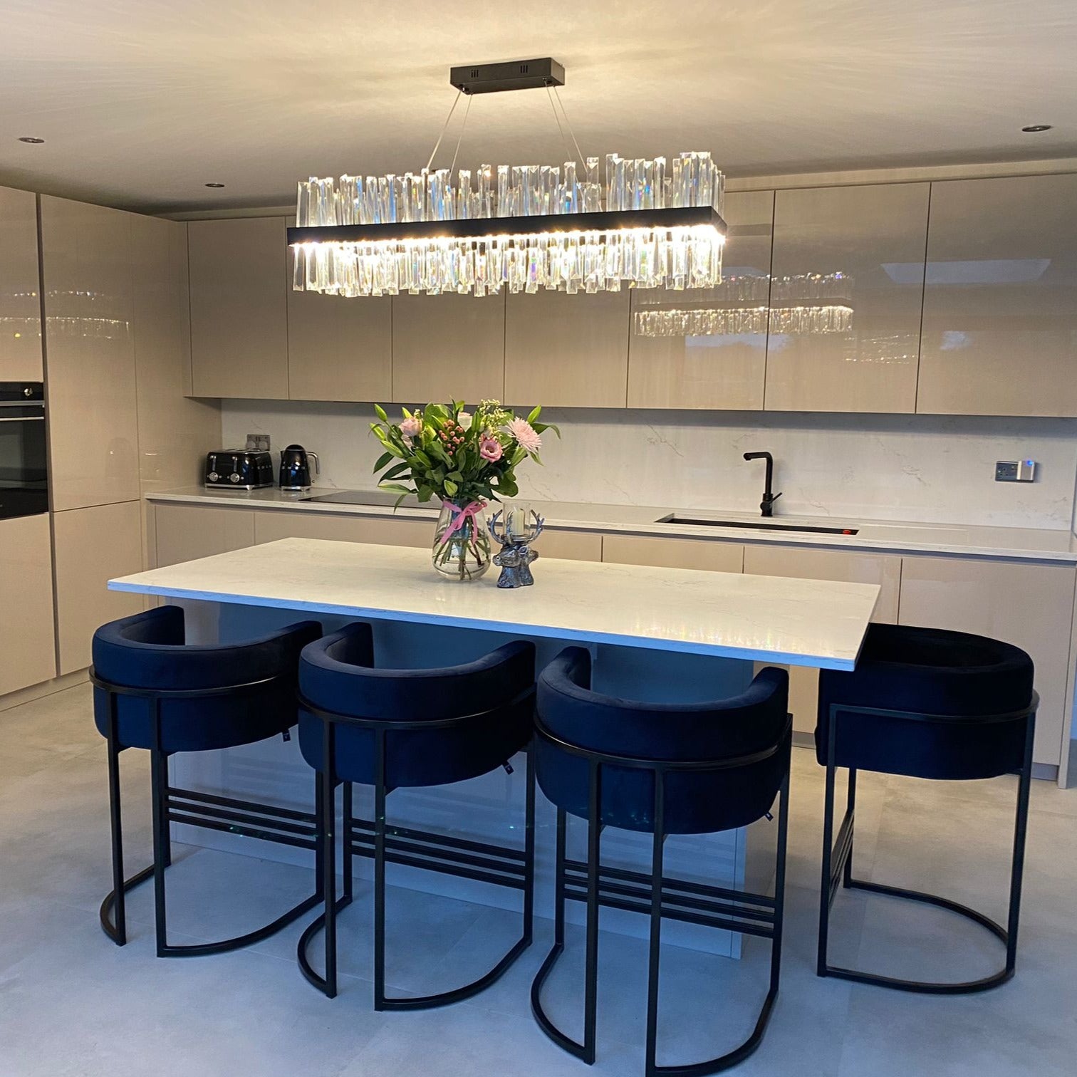 Modern rectangular crystal chandelier illuminating a luxury kitchen island with elegant ambient light