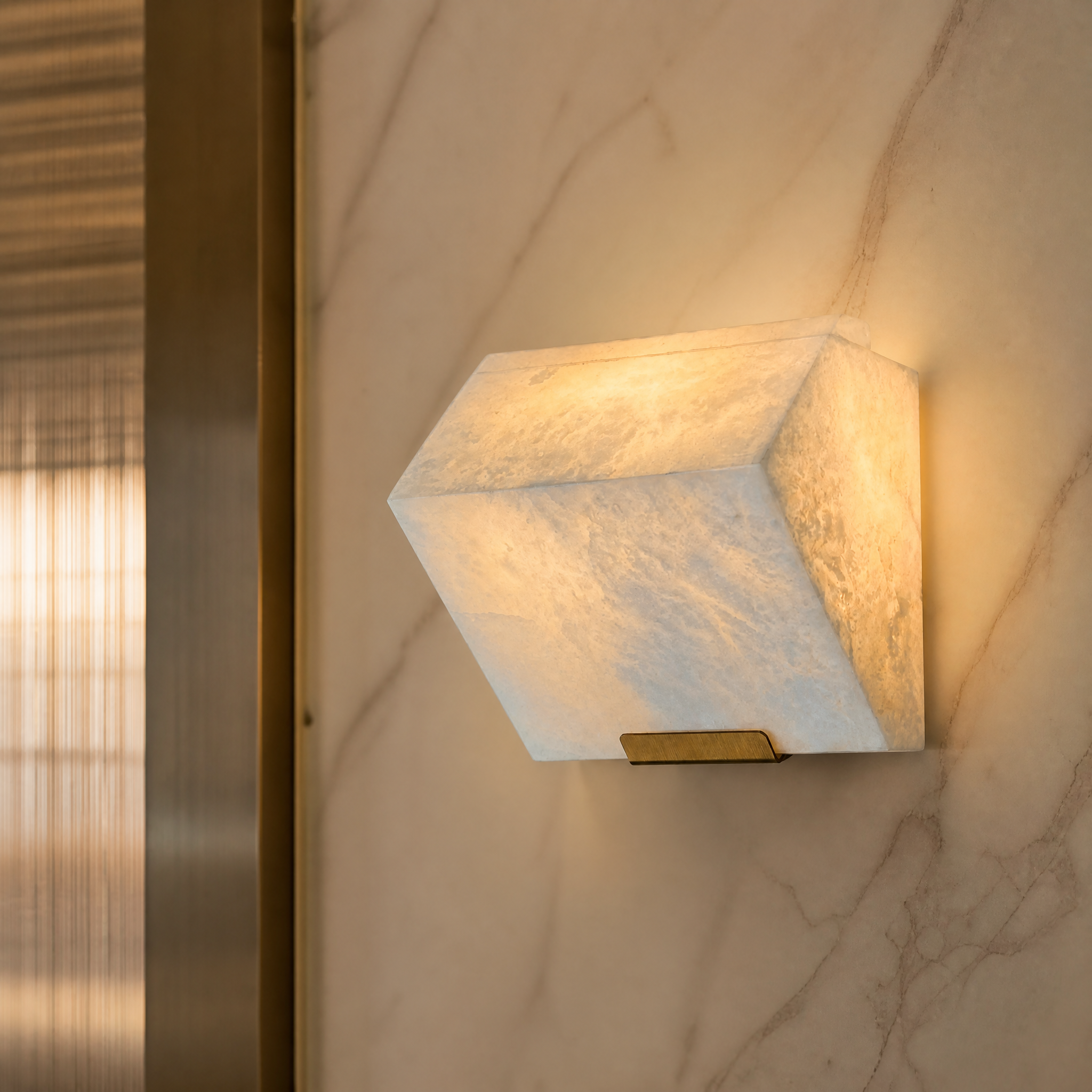 Detailed closeup of the sculpted marble texture and soft light diffusion of the VORELLI Novara wall light.